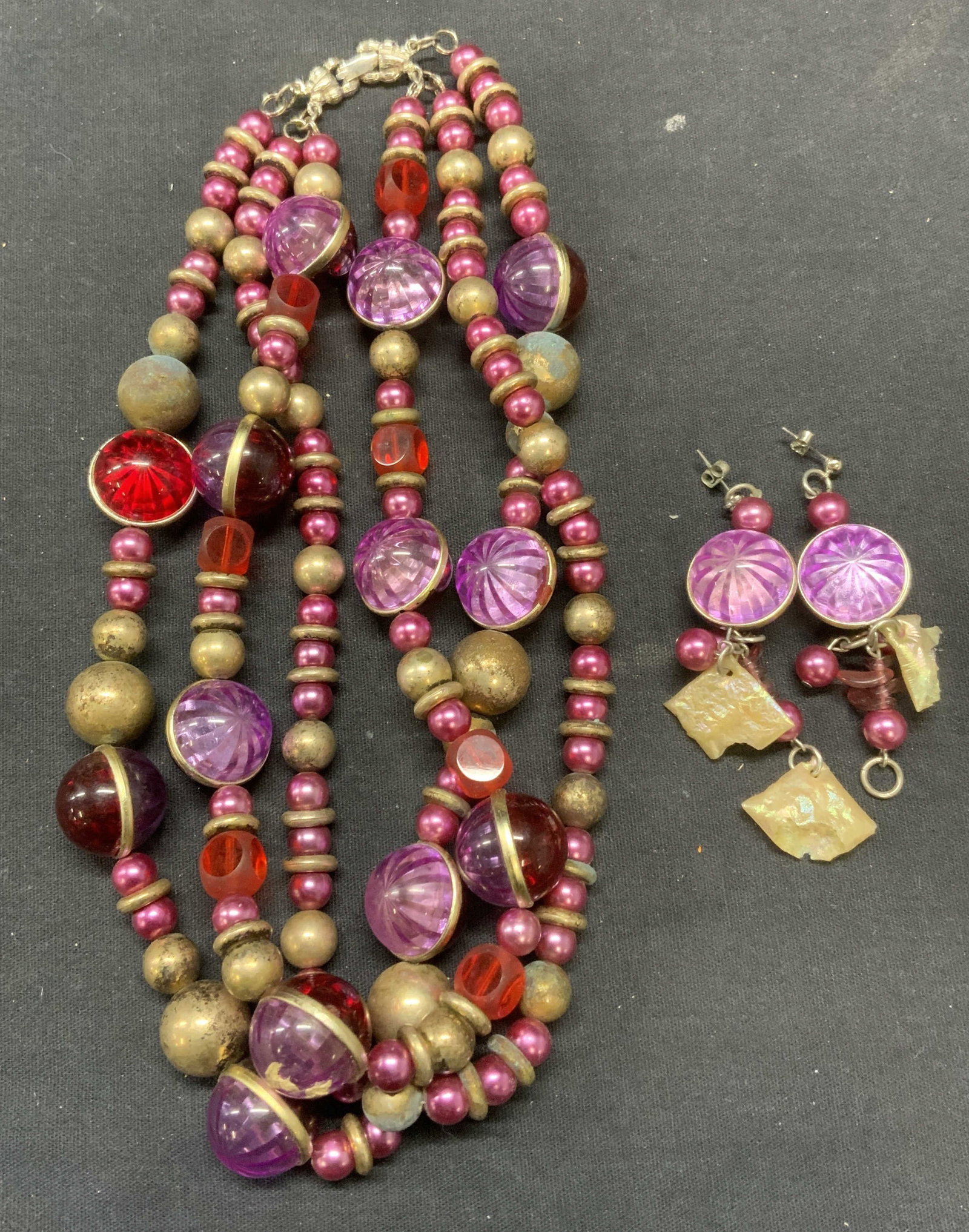 Lot 2 Purple & Red Beaded Necklace & Earrings: Lot of 2 jewelry pieces. Vintage matching purple and red beaded necklace with earrings with faux mother of pearl and silver tone accents. Necklace drop length approx. 8.5 inches. Longer earring measur