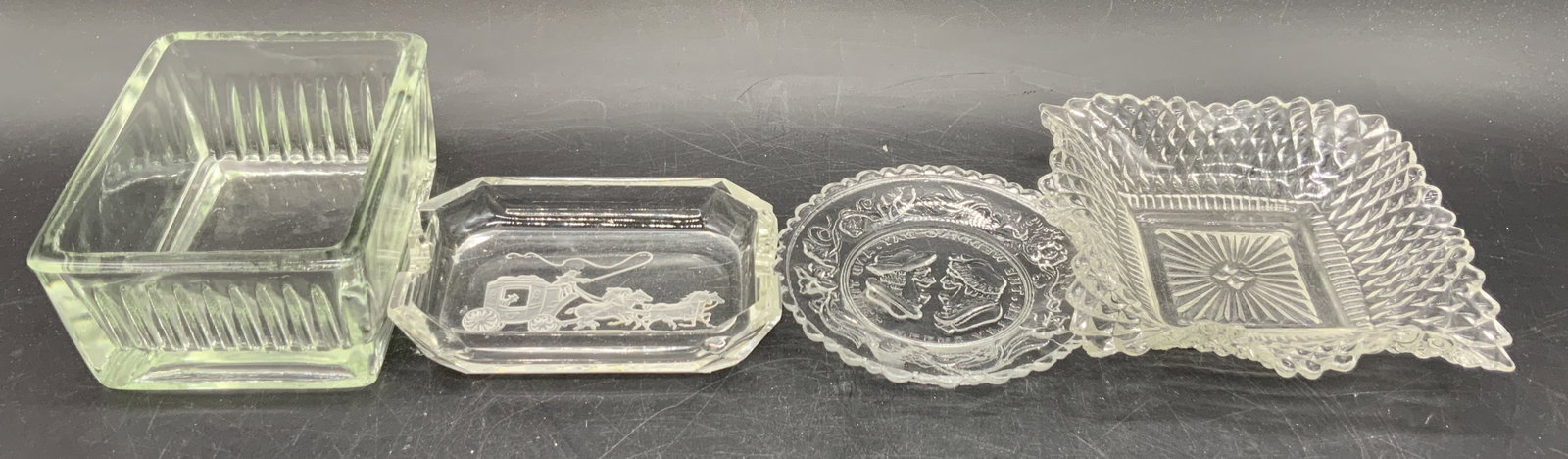 Lot 4 Vintage Clear Glass Trinket Dishes: Four vintage clear glass trinket dishes / trinket bowls. One reads THE WEDDING DAY AND THREE WEEKS AFTER and features two faces smiling at one another. Another features a horse drawn carriage motif. O