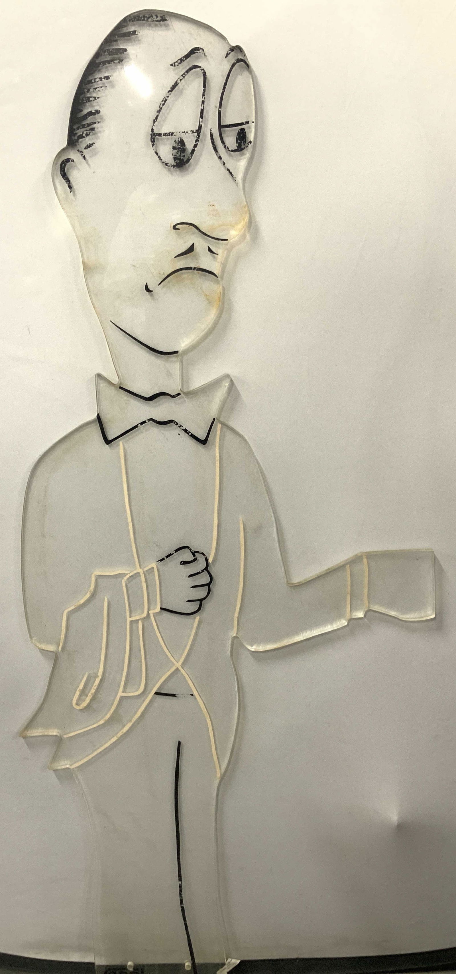 Carol Stamped 4ft Lucite Butler Cutout: Approximately 4ft tall, a butler figure cut out from lucite with black and white outlines of his suit and black facial features. All features of the butler are decals or paint. Folk art, outsider art.