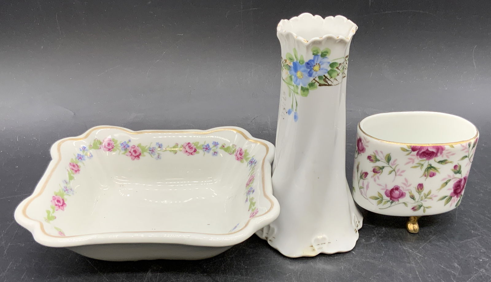 Lot 3 Signed Vintage Floral Porcelain Tableware: Three vintage signed porcelain tabletop accessories. Pieces all feature floral motifs & gilt line work, some have hand painted elements. One hat pin holder / bud vase, one tooth pick / cigarette holde