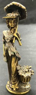 Solid Brass Art Nouveau Woman W Parasol Figural: Solid brass metal figure of a woman in long gown holding a parasol in one hand, a bag in the other and a basket of flowers next to her, figure is adorn in glitter in areas. Approx 6 inches tall. And 1