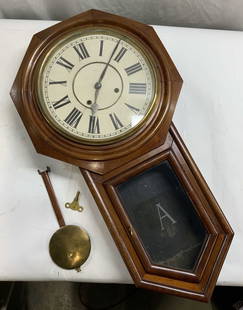 Antique Octagonal Wooden Wall Clock 32in: Antique octagonal wall clock crafted from wood, glass, and brass. Other metals present to piece. Frosted letter A to the glass door. Roman numerals to clock face. Measures approx. 32L x 5.5D x 17.75W