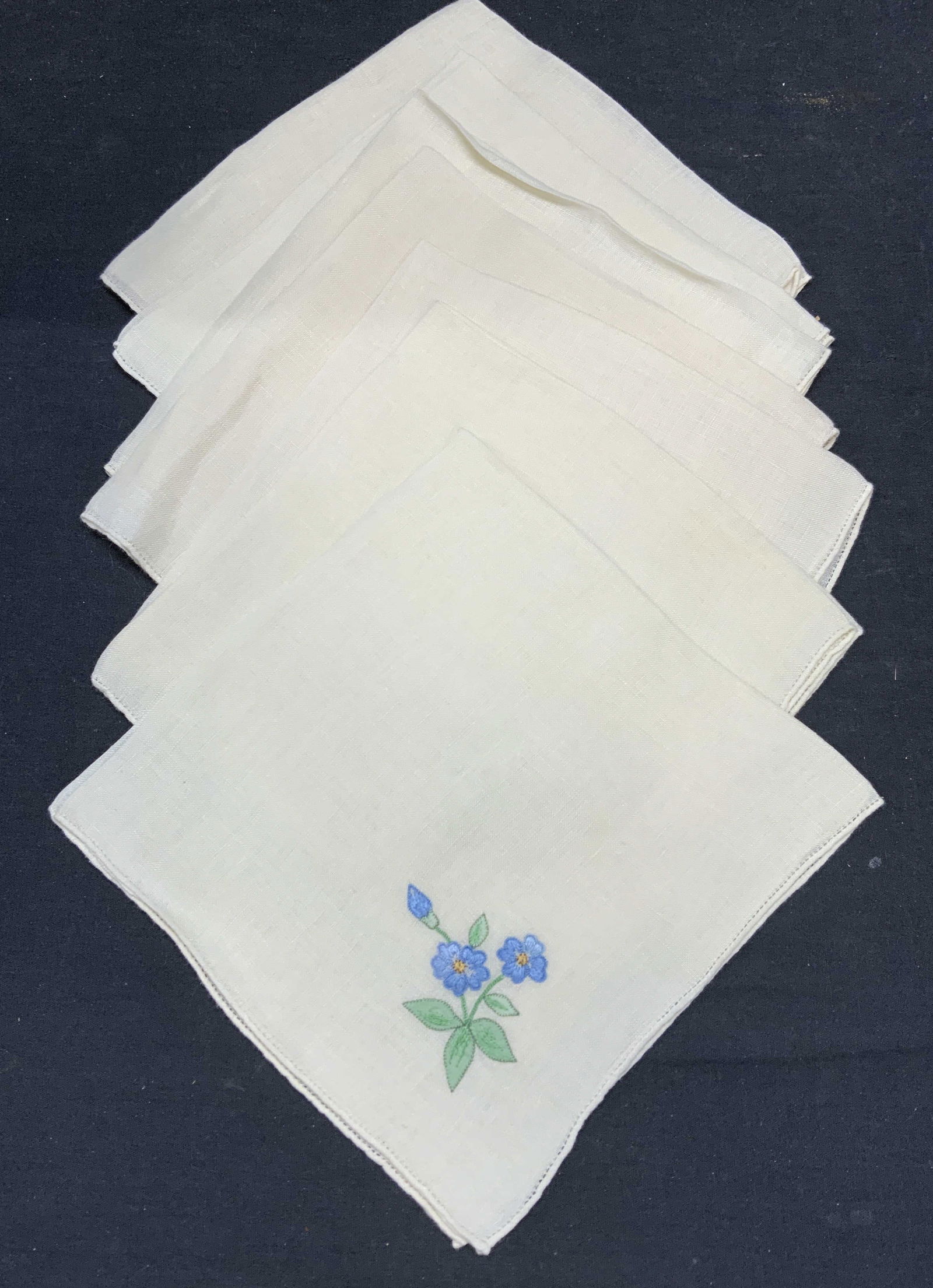 Set 7 Embroidered Linen Botanical Napkins: Set of 7 embroidered linen napkins. Off white/beige toned. Each piece has embroidered floral or botanical motif. Measure approx. 16 x 16 inches each. All pieces have some wear to material consistent w