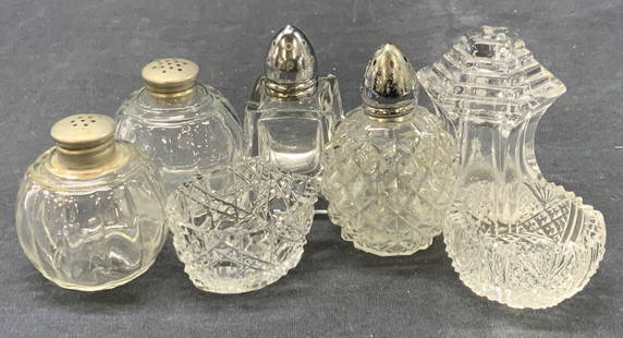 Lot 7 Cut Glass & Crystal Salt Shakers: Lot of 7 cut glass and crystal salt shakers and cellars. 2 cut crystal salt cellars at 1 inch tall. 1 pair of rounded glass shakers with pewter tops, at 2 inches tall. 1 cuboidal shape shaker, 1 resem