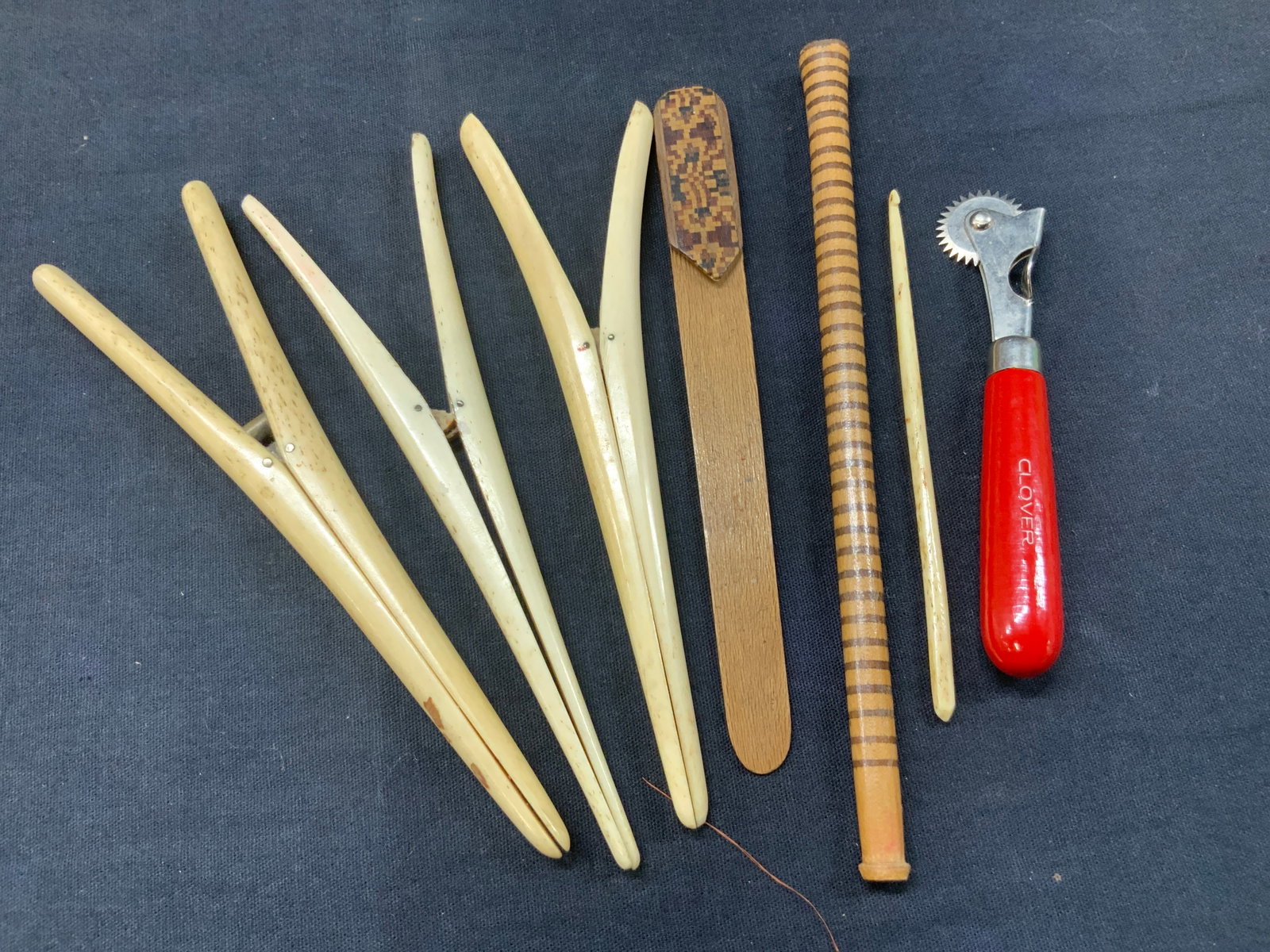 Lot 7 Vintage Sewing Tools: Lot of 7 assorted sewing accessories. 3 possibly bone made clips, 1 wooden clip a seam ripper with a bone made crochet Hook and more. Longest piece is approx 7 inches long. Evident loss to some wooden