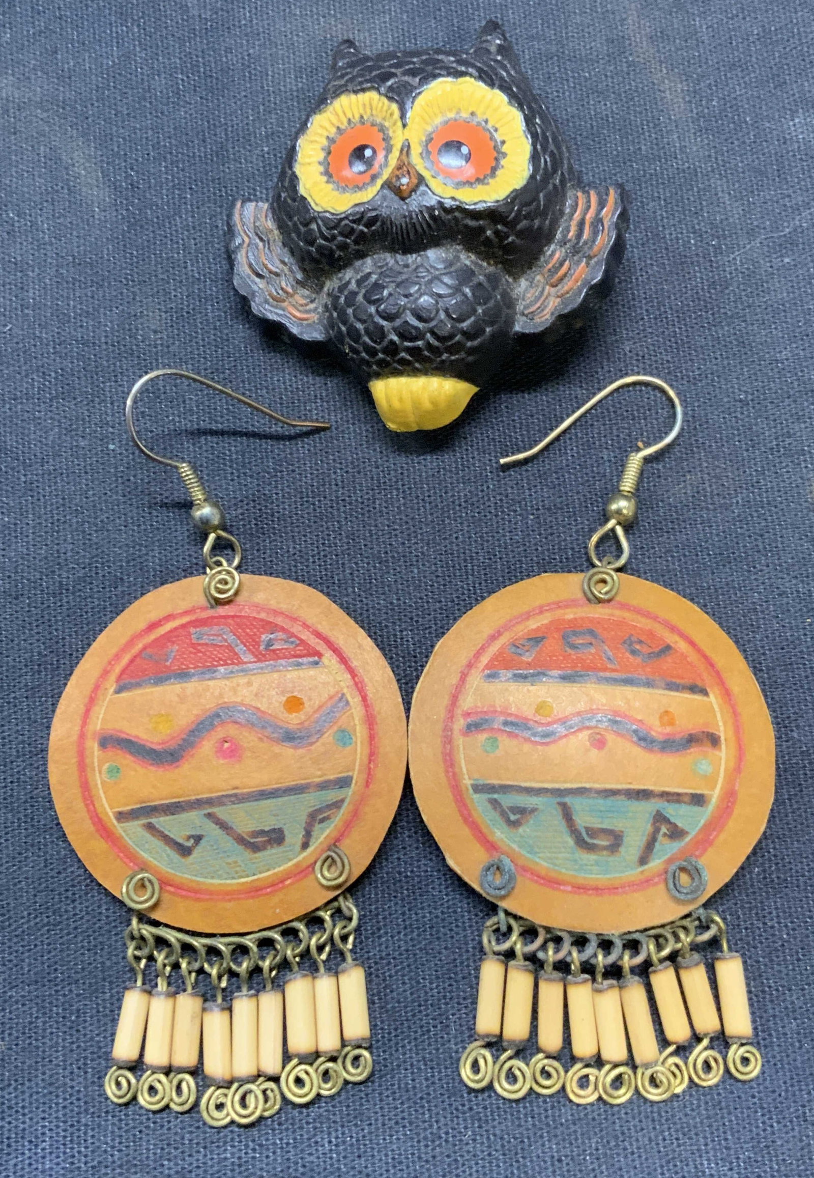 Lot 2 Owl Brooch & Dangle Earrings: Lot of 2 jewelry pieces. Resinous owl brooch. Hinge pin to underside. Measures approx. 1.75 x 1.75 inches. Tan toned beaded disc dangle earrings. Hook backing. Measures approx. 2 x 1.5 inches. Both pi