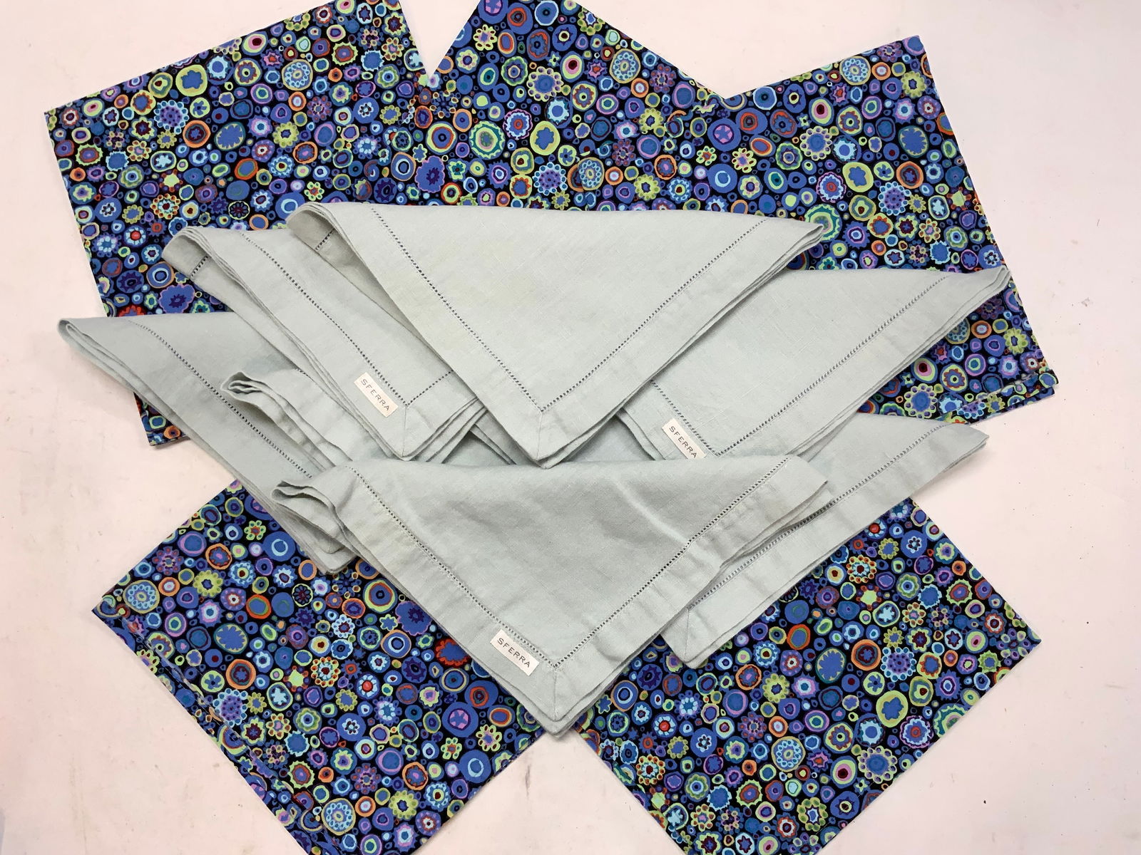KAFFE Fasset Millefiori, Sferra Linen Napkins, 12: 7 Light blue Sferra Linen Napkins, 19.75 x 19 in. Labeled. 5 hand made Kaffe Fasset Millefiori Cotton Napkins in black and purple with pops of orange, green, and pink, 19.5 x 19 in. All in very good c