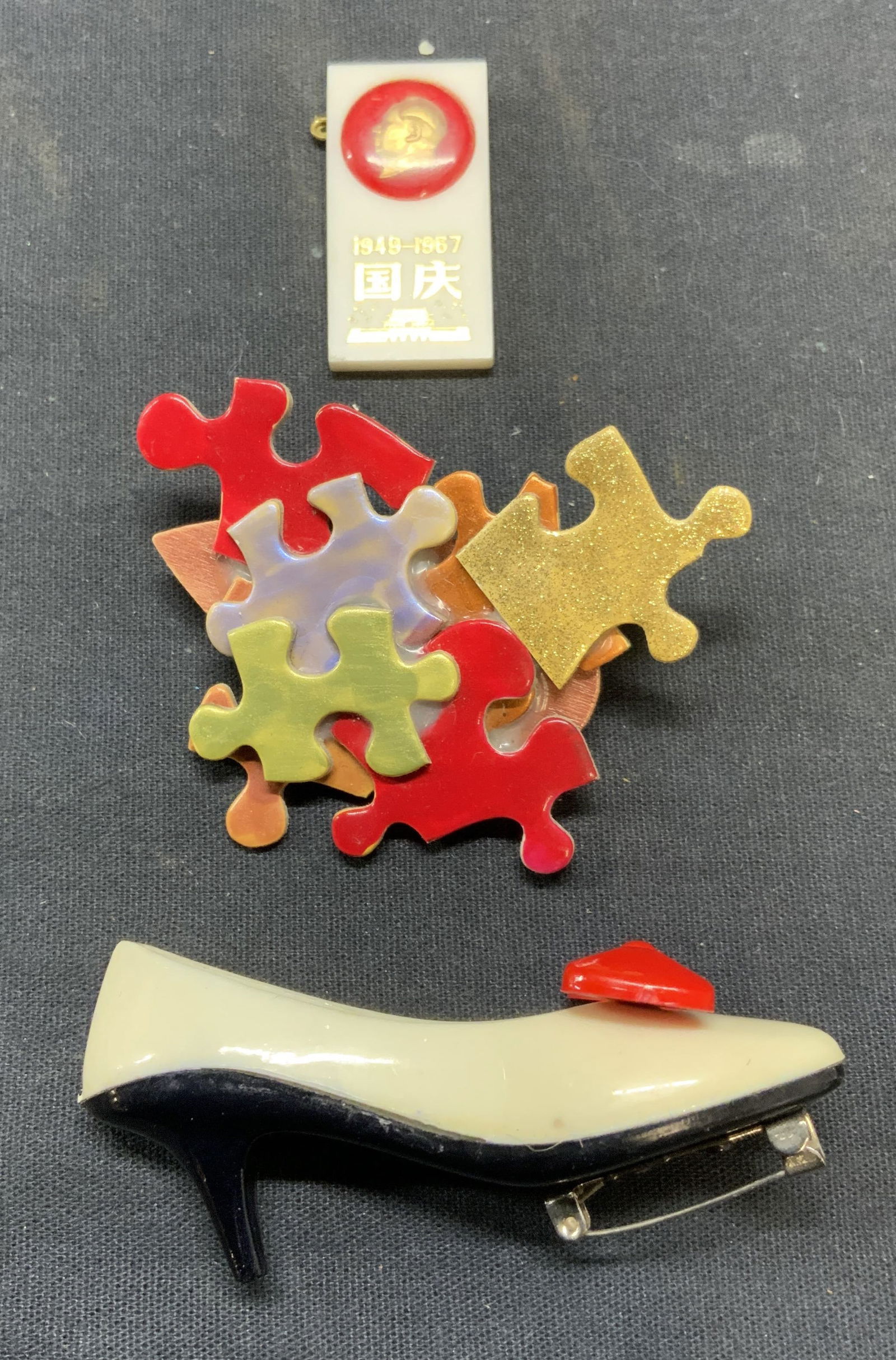 Lot 3 High Heel Brooch, Puzzle Brooch +: Lot of 3 jewelry pieces. High heel acrylic brooch. Puzzle piece brooch. Chinese acrylic brooch. All pieces have hinge pin to underside. Largest piece measures approx. 3 x 1 inches. All pieces have som