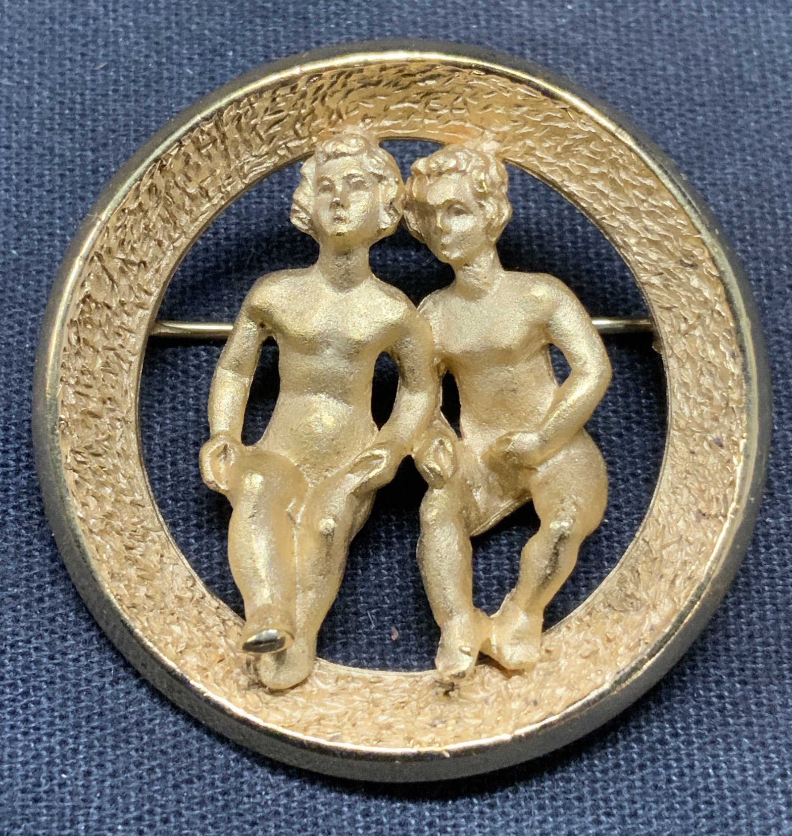 Vintage Trifari Gold Tn Gemini Zodiac Brooch: Vintage Trifari gold tone Gemini zodiac brooch. Signed to underside. Hinge pin to underside. Measures approx. 1 3/8 inches diameter. Some surface wear including scratching observed. Estate jewelry, co