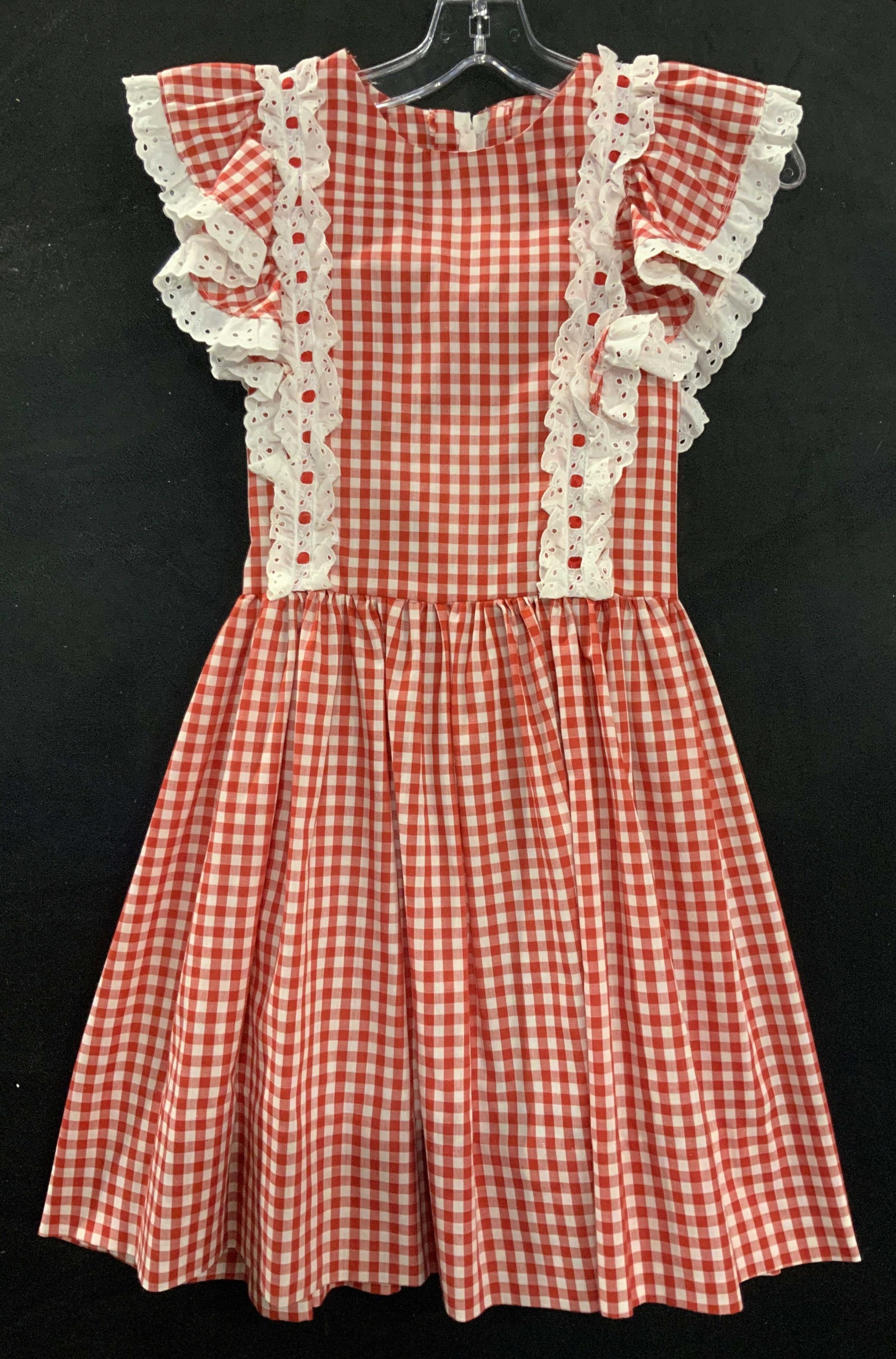 Handmade Girls Cotton Gingham Dress: Red and white gingham dress with white eyelet ruffle trim, backside zipper. Rubble trim short sleeves, pleated waist. All handmade. 31 in. Long. 22 in. Waist or larger due to a tied bow in the back. C