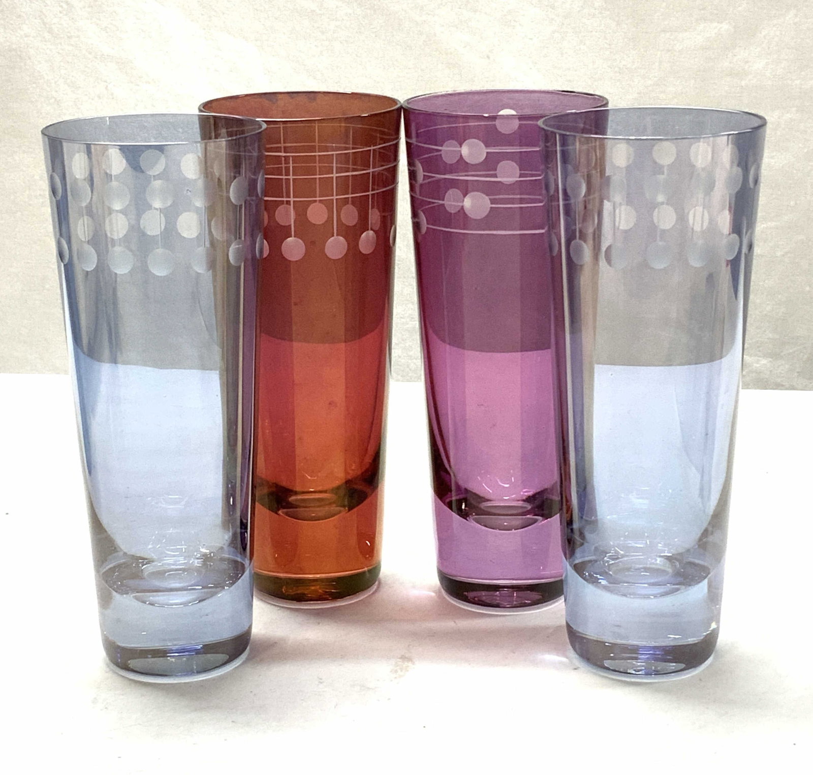 Modernist Colored Glass Tumbler Set 4: Set 4 Glass Tumblers, etched circle modernist design. 2 blue, 1 cranberry red, the other purple. Measure approx 5.5 x 2 in. Some scratches and general surface wear present. Property of Manhattan Estat