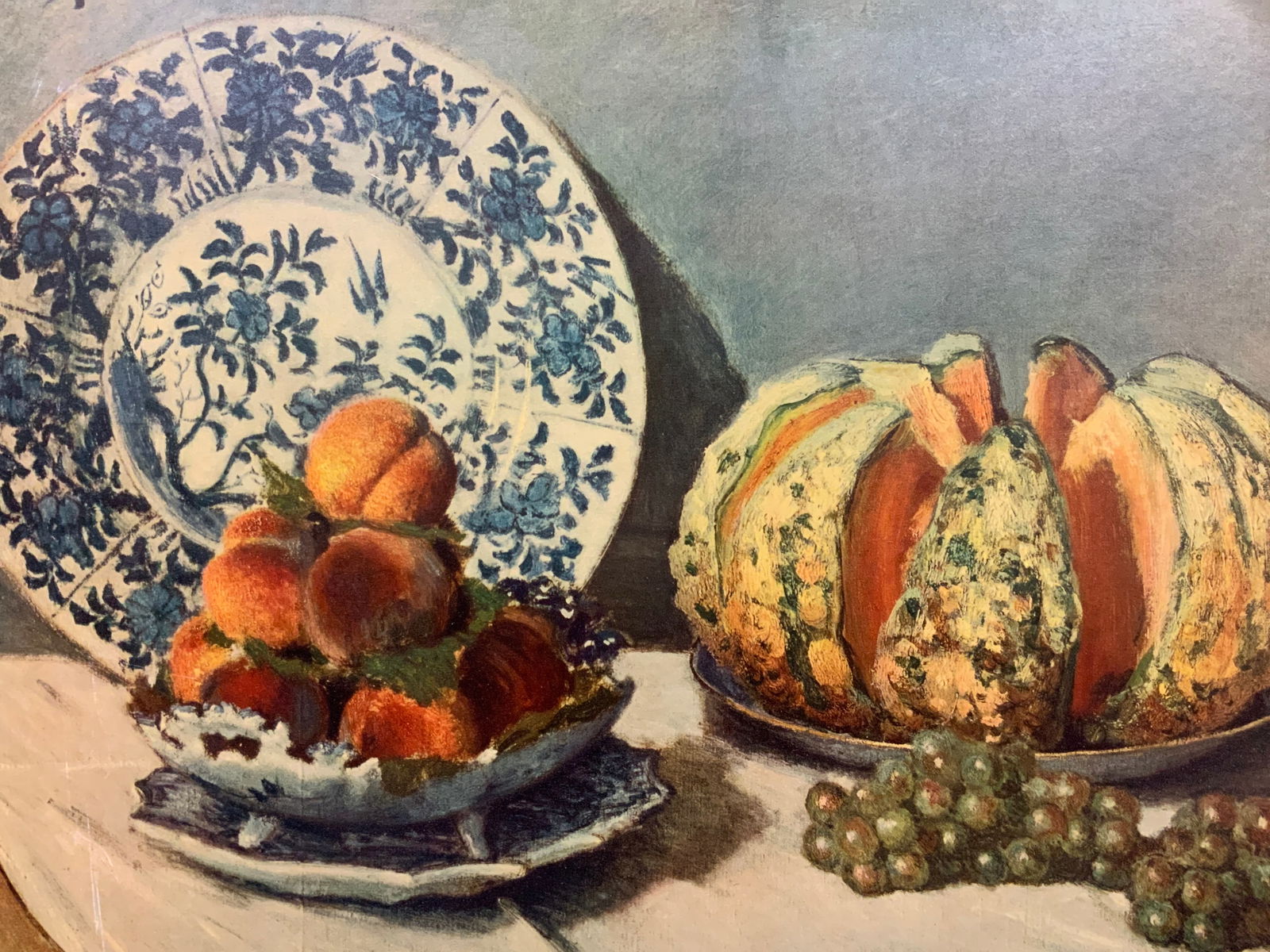 Claude Monet Still Life Mounted Lithograph: Still life lithograph by Claude Monet. Depicting various fruits on China. Mounted onto a back board. No frame, approx 20 x 28 inches. Modest discoloration and wearing to edges and corners. Claude Mone