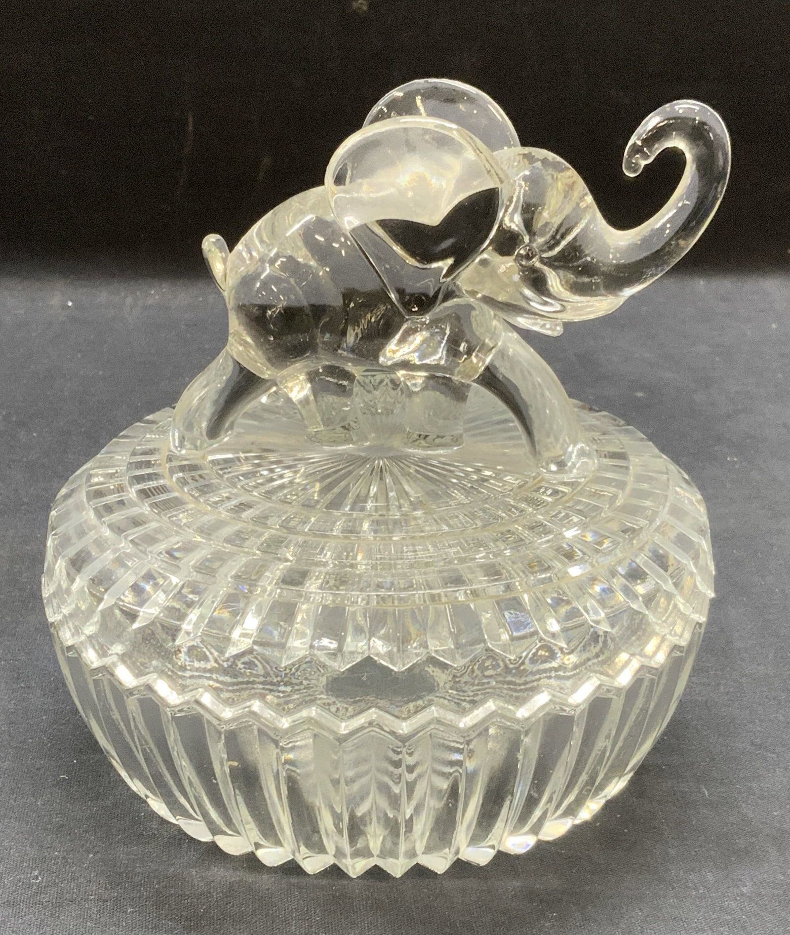 Lidded Cut Glass Elephant Bowl: Ribbed cut glass bowl with elephant motif on lid. Measures approx. 5.75 x 6 inches including lid. Some surface wear including scratching observed. Glass bowl, lidded glass bowl, elephant bowl, ribbed 