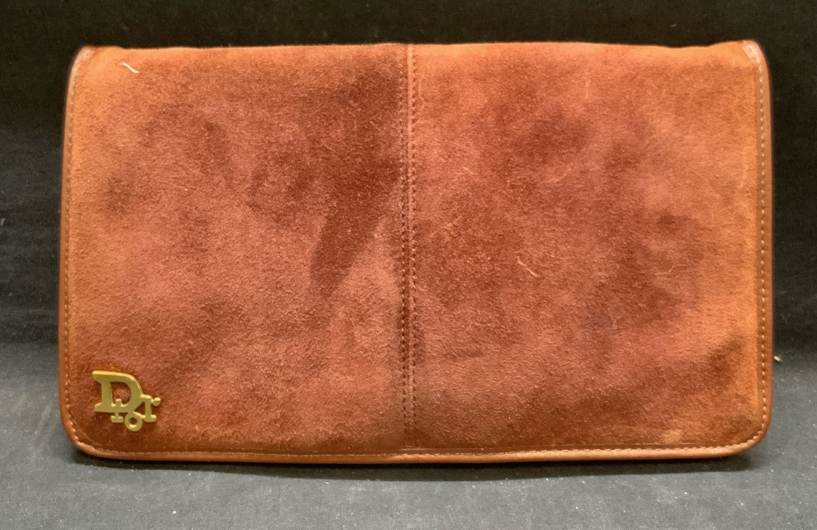 Dior Burgundy Suede & Leather Handbag: Dior burgundy toned suede and leather handbag. Measures approx. 6 x .5 x 9.5 inches. Fold over flap with button closure. 1 zippered pocket to interior. Signed on hardware to exterior. No other signatu