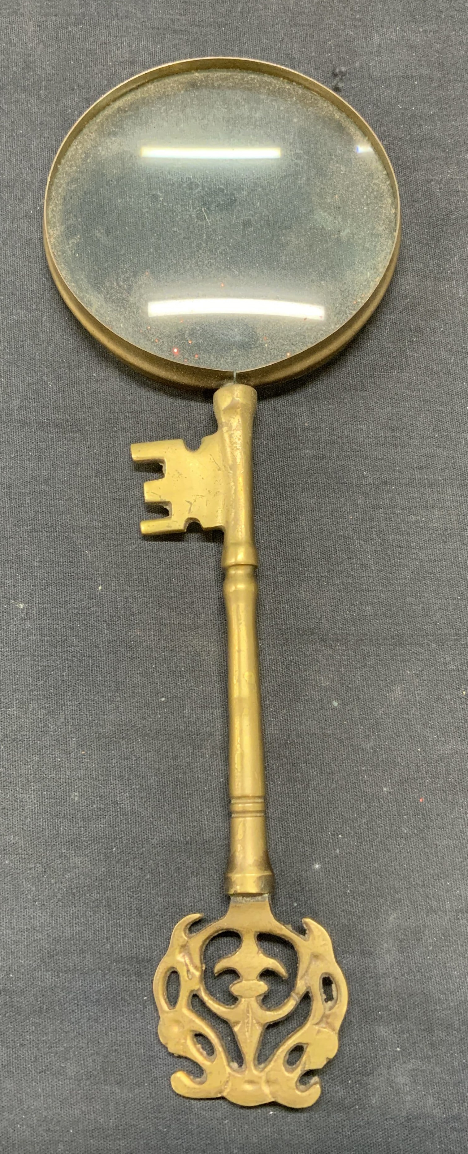 Vintage Brass Key Handle Magnifying Glass: Vintage brass magnifying glass with key shaped handle. Piece has weight. Measures approx. 11 x 3.75 inches. Some surface wear including scratching observed. Magnifying glass, vintage magnifying glass,