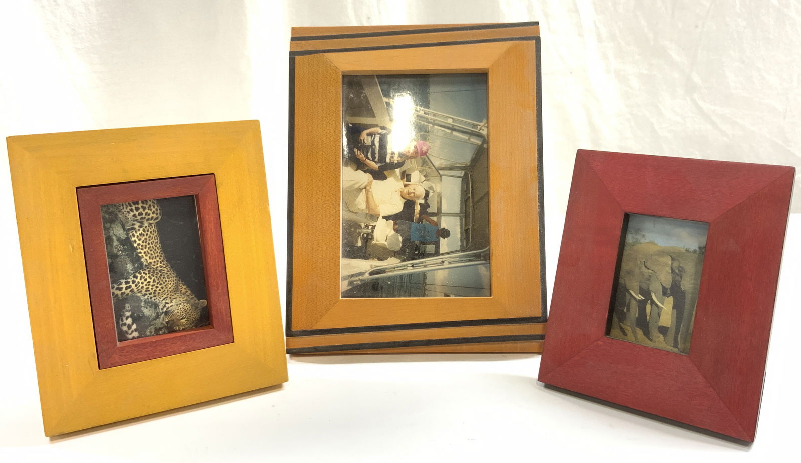 Lot 3 Standing Wooden Picture Frames: Lot includes 1 red frame, 1 yellow & red frame, & 1 beige & red frame. Each frame appears to be wooden. Frames each have stands on backsides. Largest frame measures approximately 8.5 inches tall 6.5 i