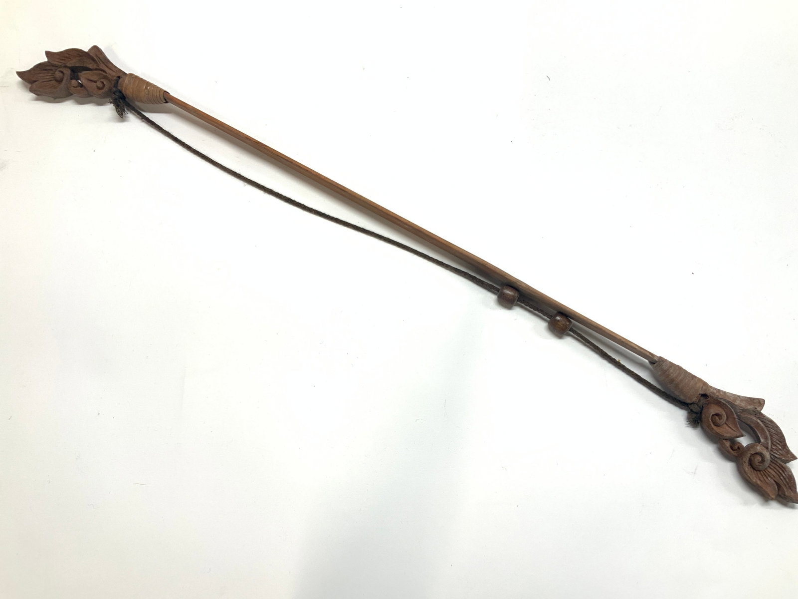 31 Inch Carved Wooden Bow Replica: Approximately 31 inches long. Carved wooden bow replica with scroll designs on outer ends of the bow and a black cord with wooden beads as the spring. Moderate wearing to wood on ends of the bow Woode