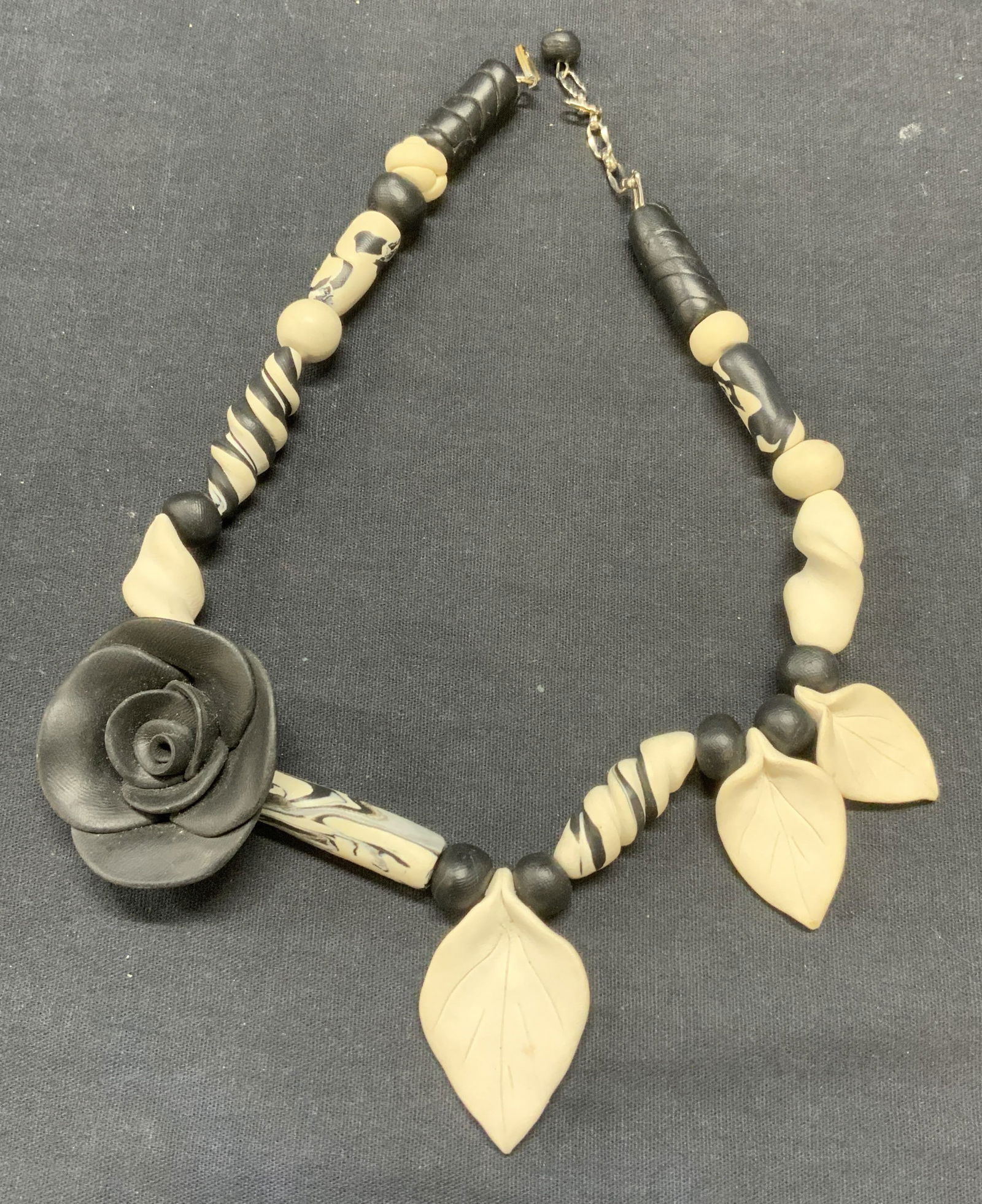 Handmade Black & White Flower Necklace: Handmade black and white toned clay necklace with flower and leaf pendants. Drop length approx. 7.5 inches. Some surface wear including scratching observed. Estate jewelry, costume jewelry, cocktail j