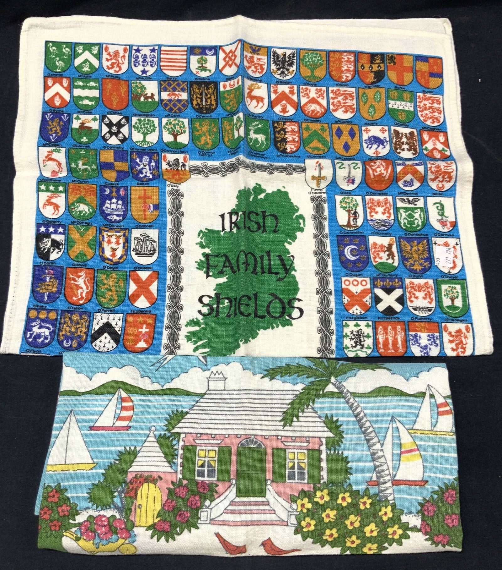2 Graphic Linen Tea Towels, Bermuda & Ireland: Lot of 2 graphic linen tea towels, 1 marked Irish Family Shields with the various Irish family crests throughout in full color and 1 tea towel, marked Bermuda, depicting a house with an ocean in the b