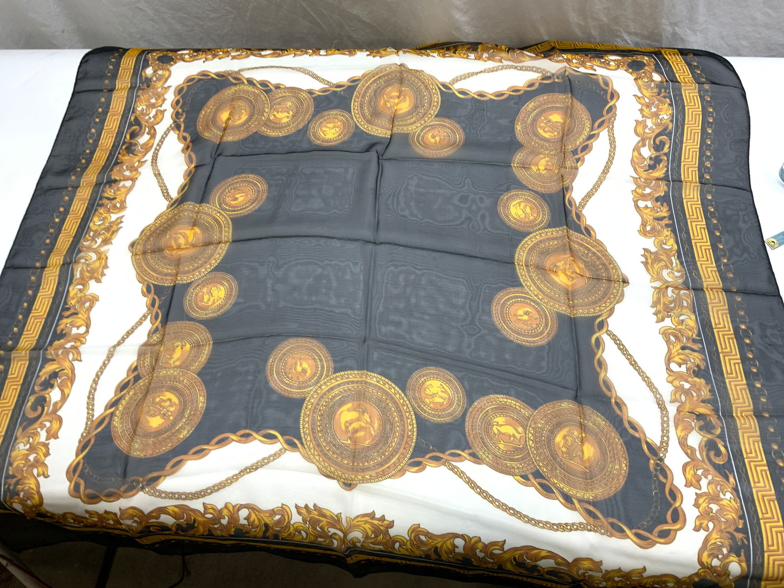 Greek Key, Acanthus Leaf & Coin Motif Scarf: 40 in. sheer polyester scarf with zodiac coins, Greek key, and acanthus leaf design. Black, gold, and white. Fabric wear in certain areas. Up cycle fabric Property of Manhattan Estate DuPont Heir. Sca