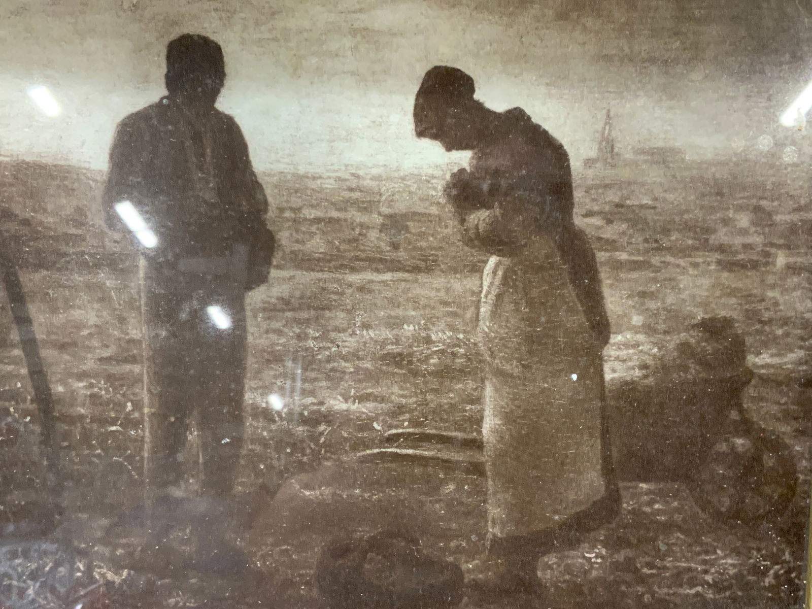 Sepia Toned The Angelus Lithograph: Sepia toned lithograph of The Angelus, By Jean Francois Millet. Depicting a two outside in a field over a back of potatoes as they pray, Framed in a wooden frame, Approximately 10 x 12 inches window m