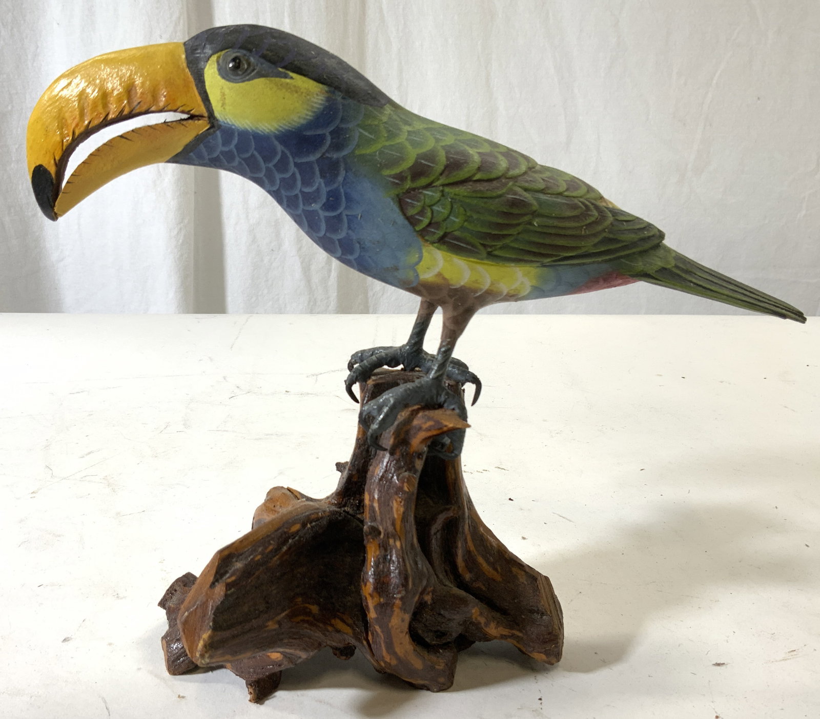 Hand Crafted Wooden Toucan Figural: Figure depicts a toucan perched on a branch. Piece appears to be hand crafted & hand painted. Painted detail shows texture of feathers. Piece Measures approx 10 inches deep, 8 inches tall 5 inches wid