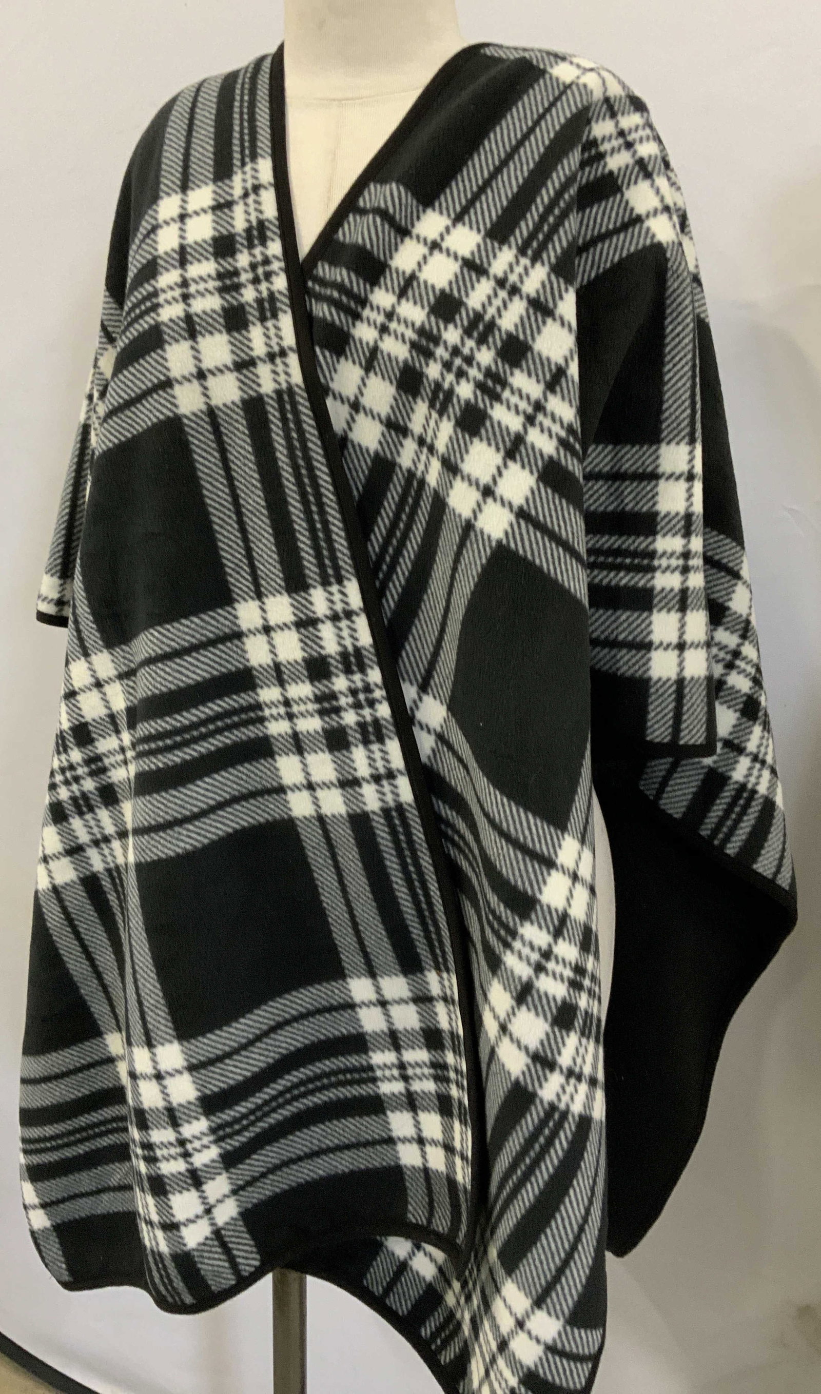 Black and White Plaid Fleece Cape: Soft plush polyester fleece cape, one size fits all. Black side length is 31 in. Total width 46 in. Exterior is a black and white plaid design. Interior is all black. Label has been removed. In like n