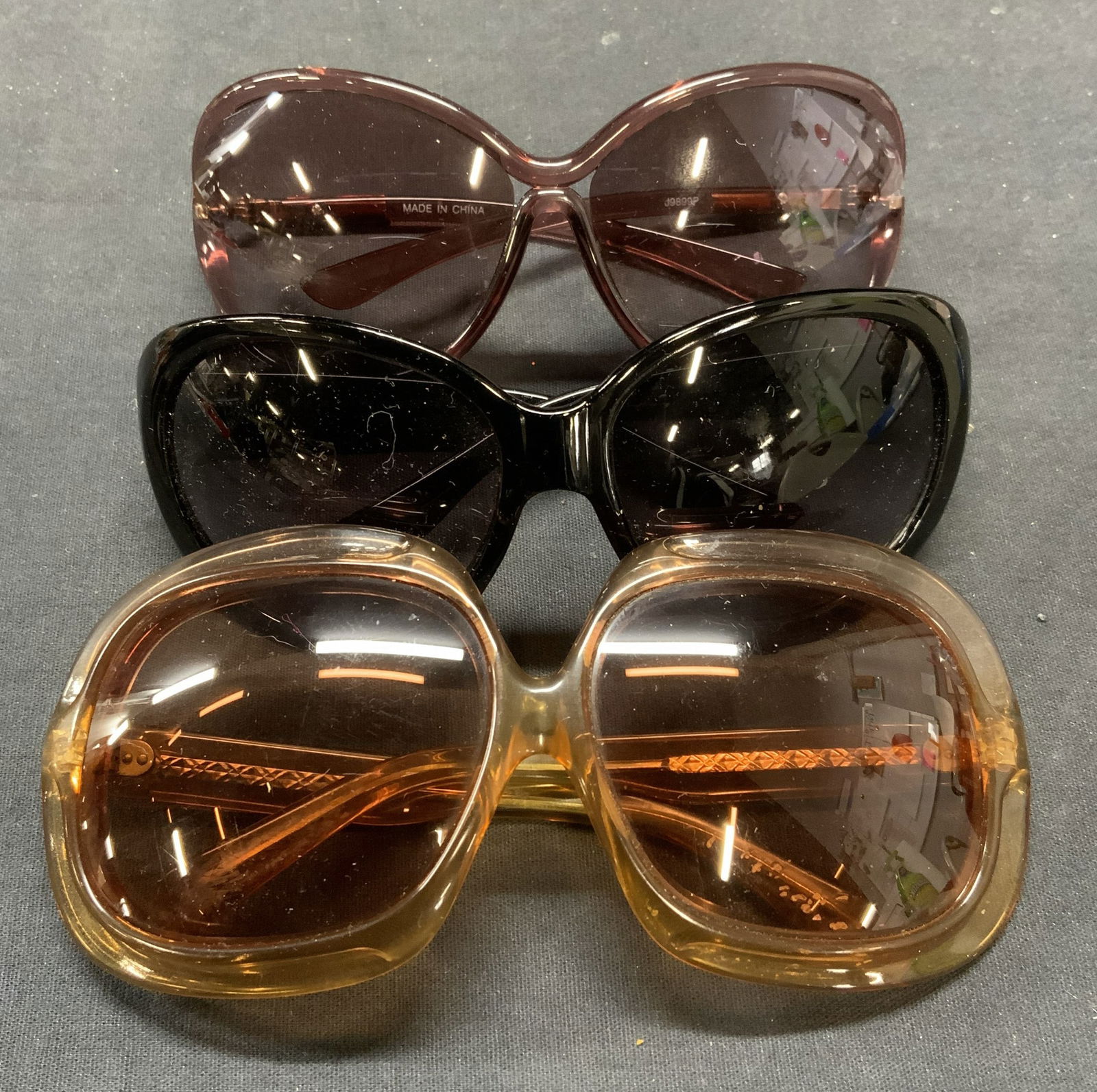 Lot 3 Purple, Tan, Black Sunglasses: Lot of 3 sunglasses. Purple, black with crystal decoration, and tan toned acrylic frames. Largest pair measure approx. 6.25 inches wide, arm approx. 5.5 inches long. All pieces have some surface wear