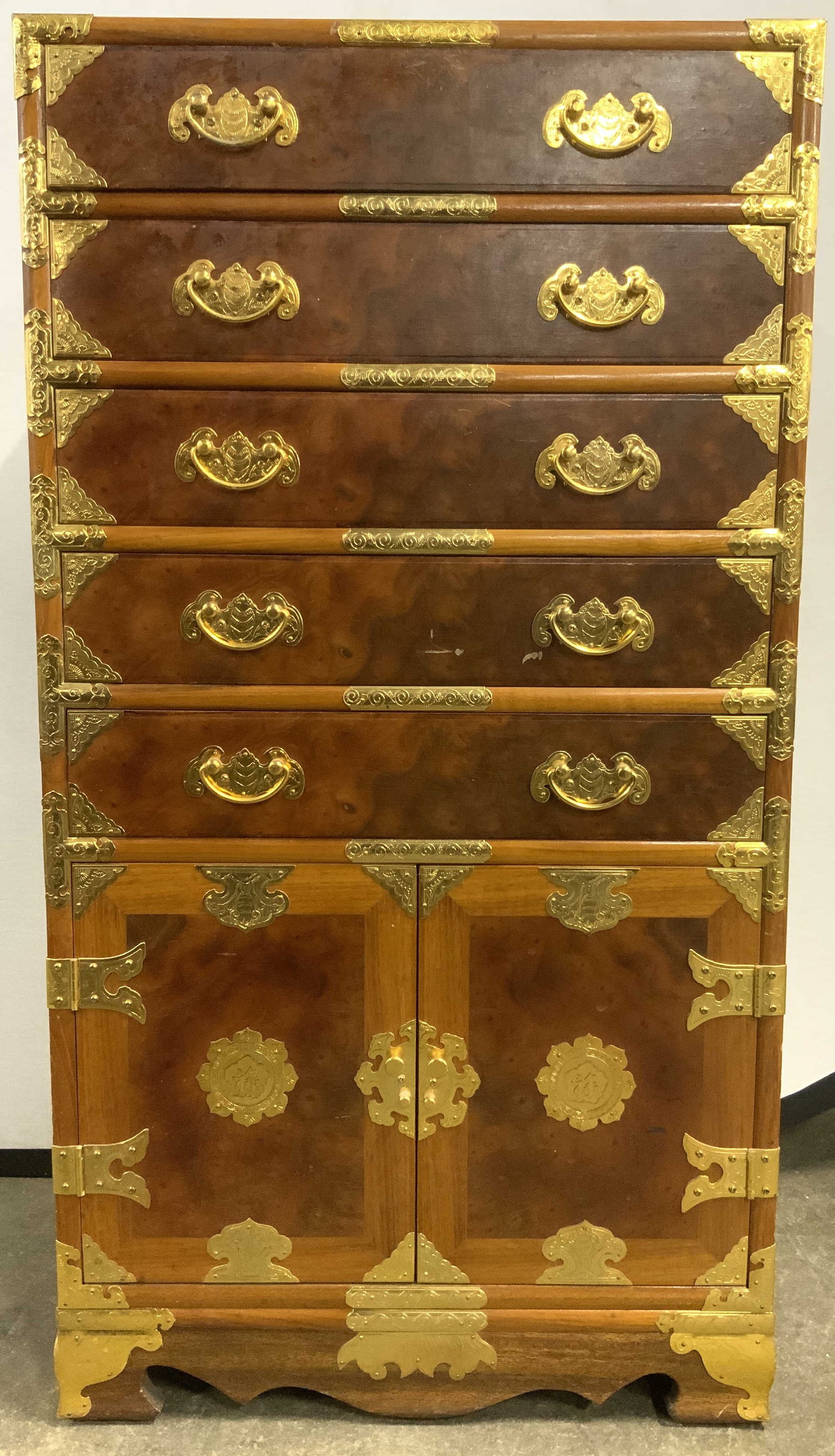 Vntg Asian Burlwood Campaign Chest W Handles: Campaign chest is vintage Burlwood. Piece is adorned with gold toned brass ornamentation. Chest has 5 drawers each with handles which resemble bats as with the handles on each side. Lower area of piec