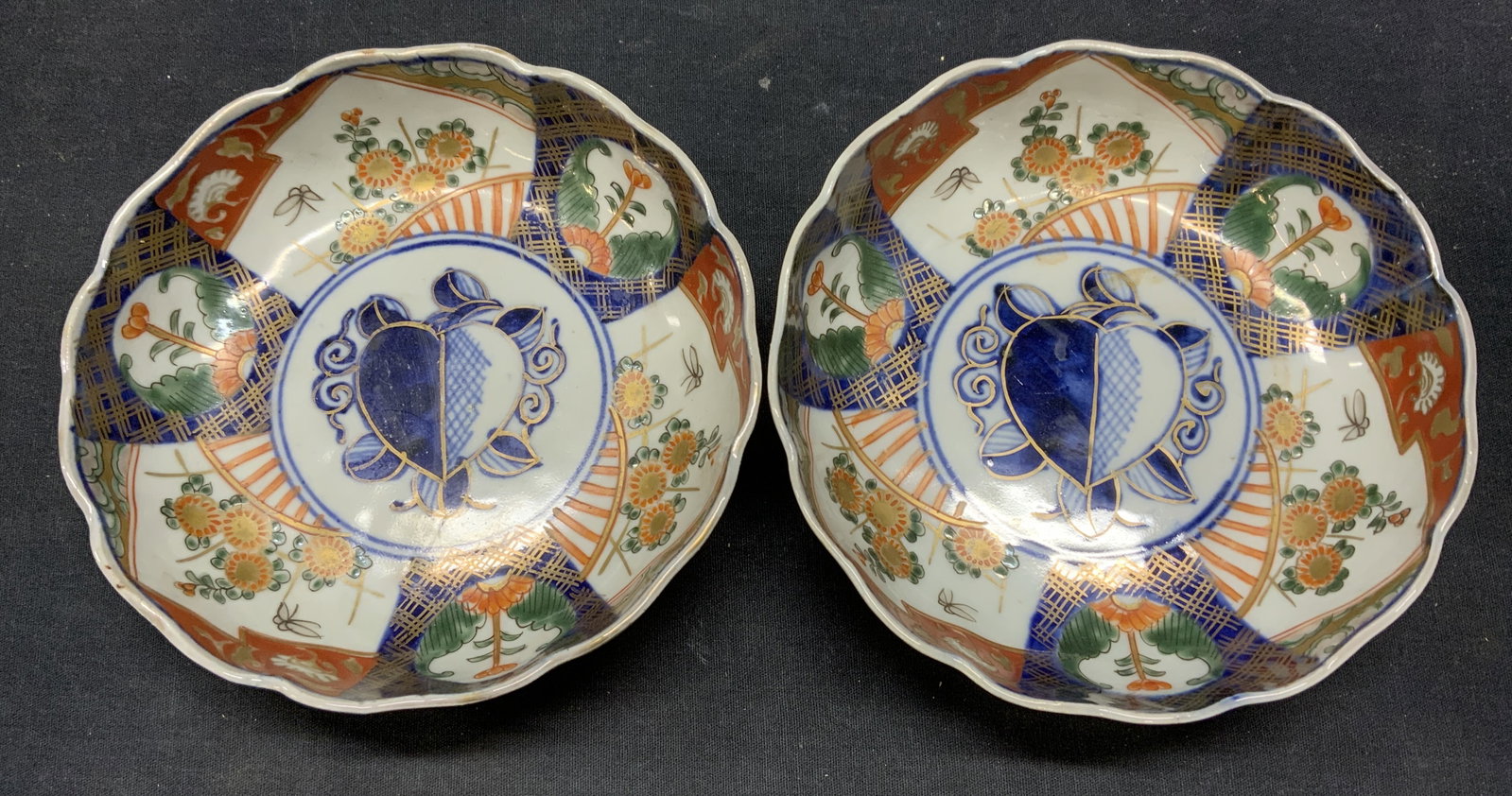 Pair Antique Japanese Imari Porcelain Bowls: Pair of antique Japanese imari porcelain bowls. Hand painted in hues of blue and red with gilt decoration and botanical motifs. Scalloped rims. Measure approx.6 x 2 inches each. Both pieces have some 