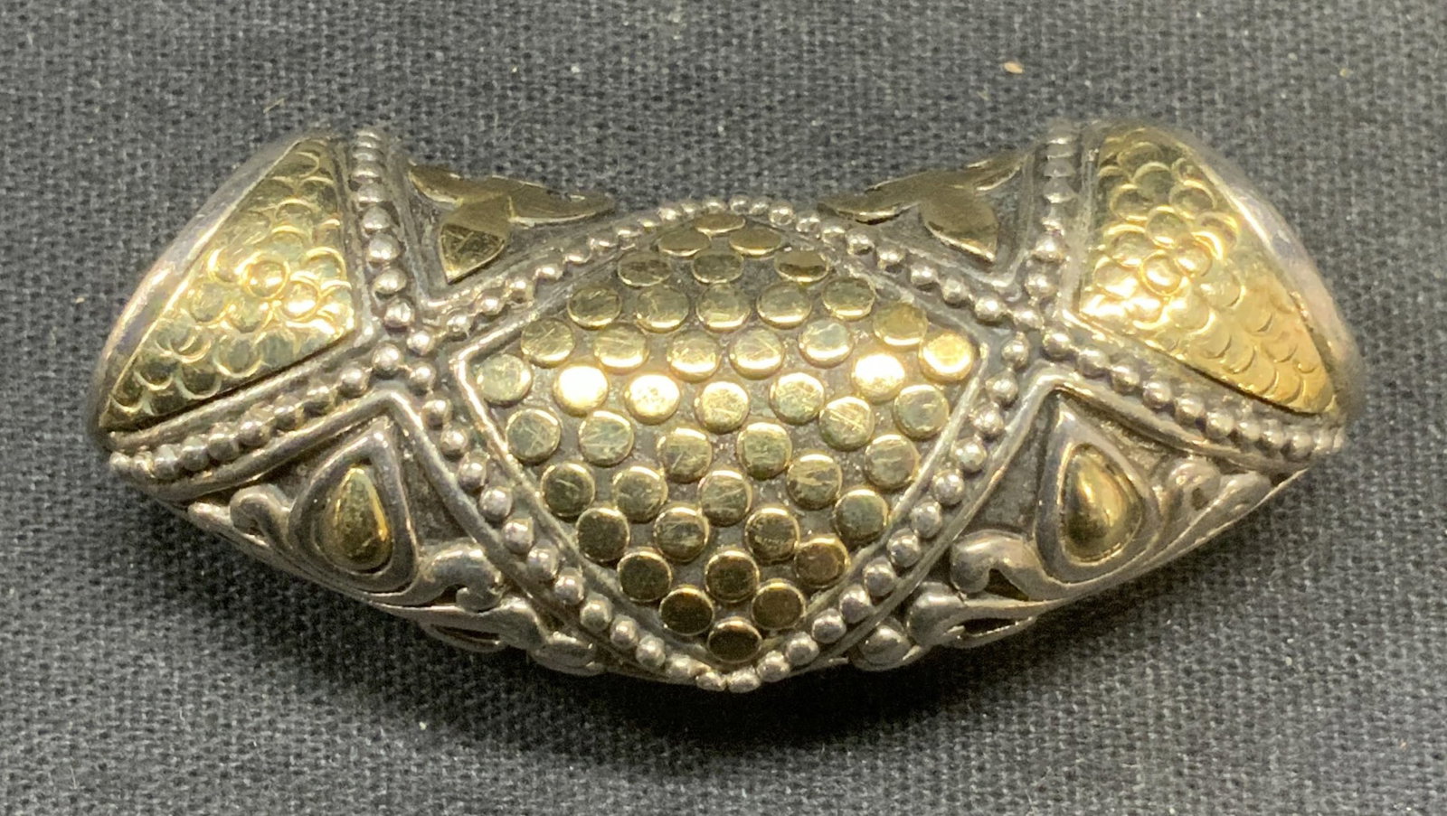 John Hardy Sterling Silver & 18K Gold Pendant: John Hardy sterling silver and 18K yellow gold pendant. Ornate embossed pattern. Signed to reverse, marked 925, 18k. Measures approx. 2 x .75 inches. Total weight 28.7 grams. Includes jewelry pouch. S