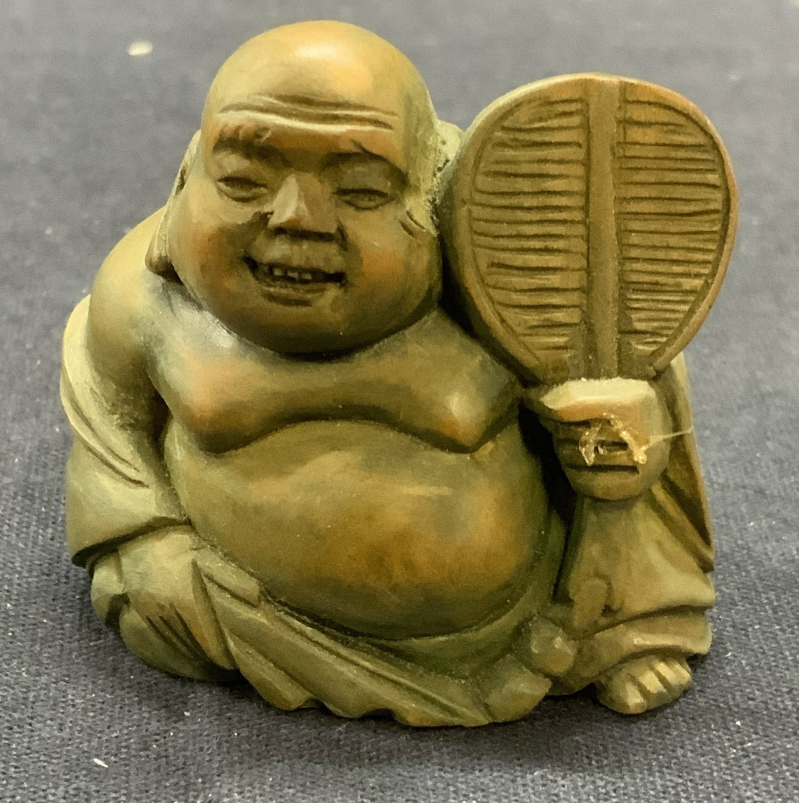 Vintage Hand Carved Buddha Netsuke: Vintage hand carved Buddha figural netsuke. Painted green. Material unknown. Measures approx. 1.75 x 1 x 1.5 inches. Some surface wear including scratching observed. Glue residue on hand. Property of 
