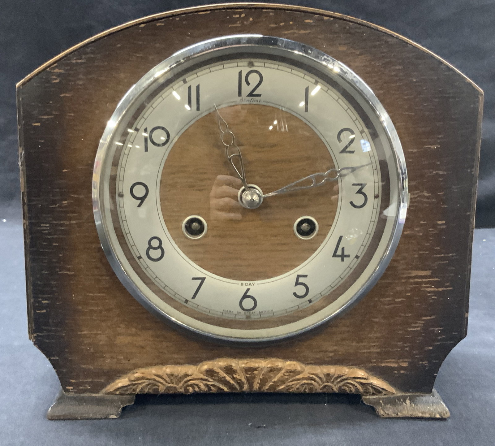 Perivale Antique Wooden Clock, England: Antique dark wooden clock with side feet and ornate carving to bottom center of obverse side. Marked on interior hardware, Perivale, made in Great Britain. Approx 8.5 inches tall and 9 inches long and