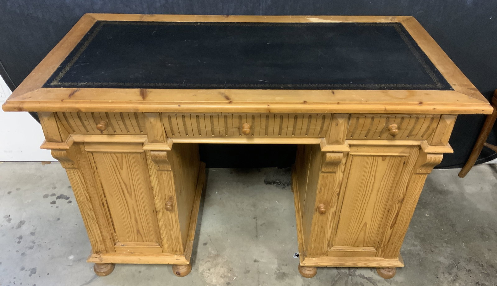 Vintage Leather Top Wooden Desk: Desk is vintage and wooden. Piece has black toned leather top with gold toned detail around edges. Desk has 6 drawers, 3 of which are behind cabinet doors. Other side has shelf inside cabinet. Drawers