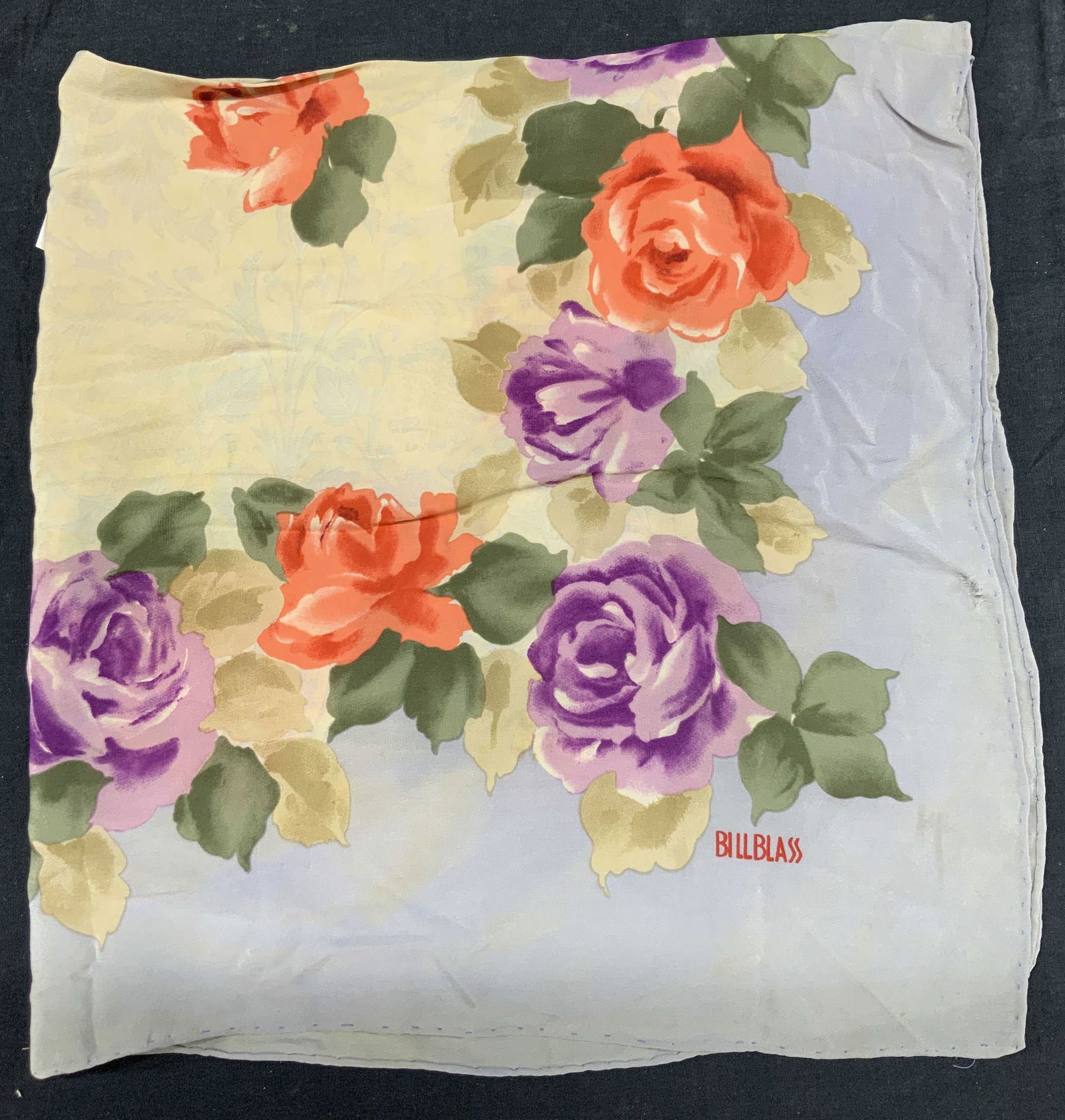 Bill Blass Hand Rolled Edge Silk Floral Scarf: Marked Bill Blass. Silk scarf. With hand rolled edges and purple and red rose motif with center gold tones. Approx 29 x 27 inches. Evident blemishes and holes to scarf. Silk scarf, scarf, estate acces