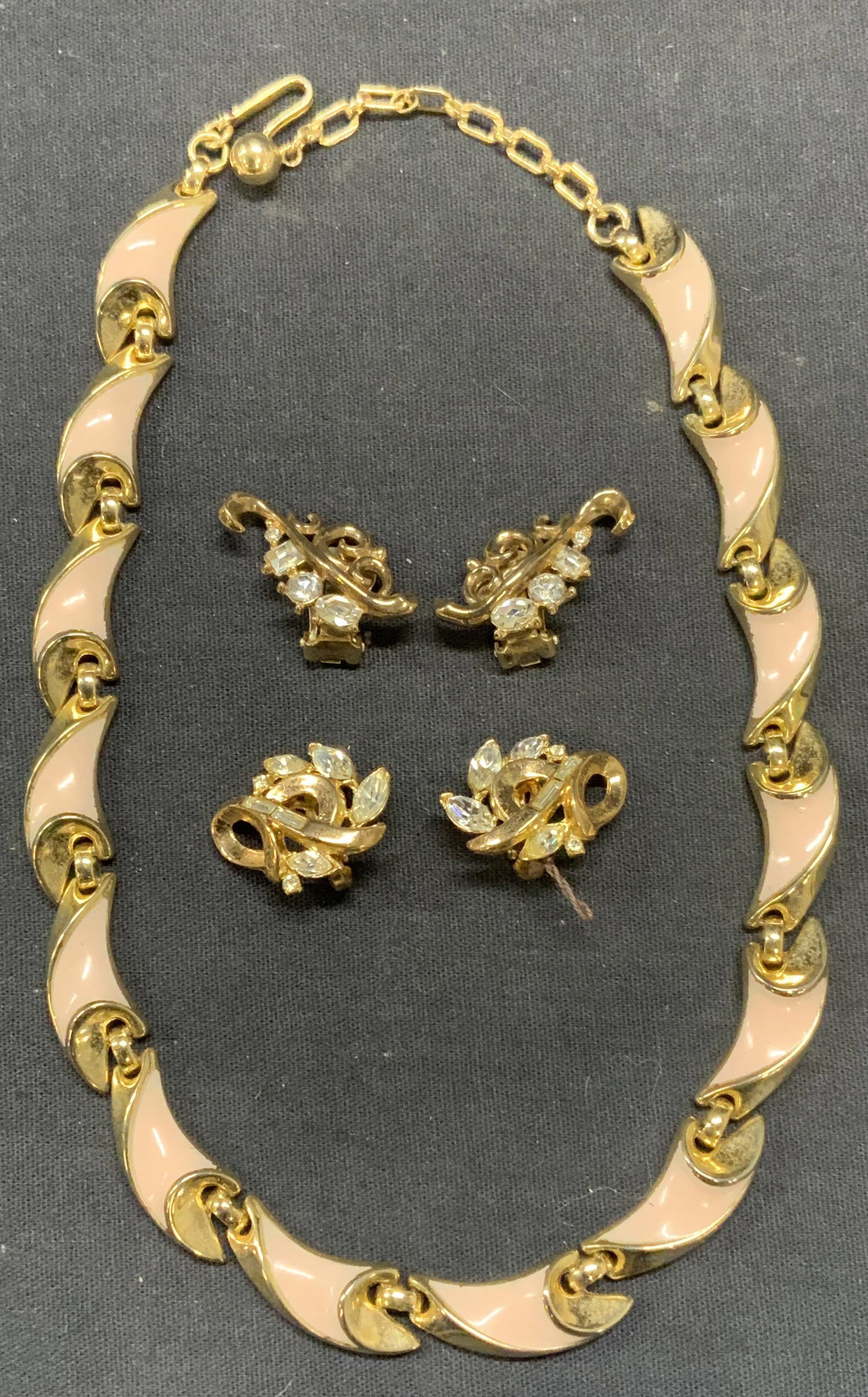 Lot 3 Vintage Trifari Earrings & Necklace: Lot of 3 jewelry pieces. 2 pairs of vintage gold tone crystal Trifari earrings. Signed to backings. Clip on earrings. Larger pair measure approx. 1 inch long. Vintage gold tone pink enameled Trifari n