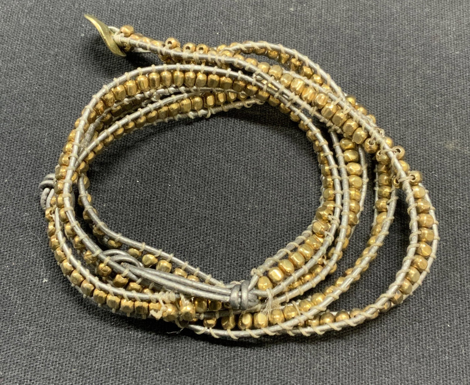 Vintage Gold Tone Beaded Necklace: Vintage gold tone beaded necklace on gray cord. Drop length approx. 13.5 inches. Surface wear including scratching and loss to beading observed. Estate jewelry, costume jewelry, cocktail jewelry, fash