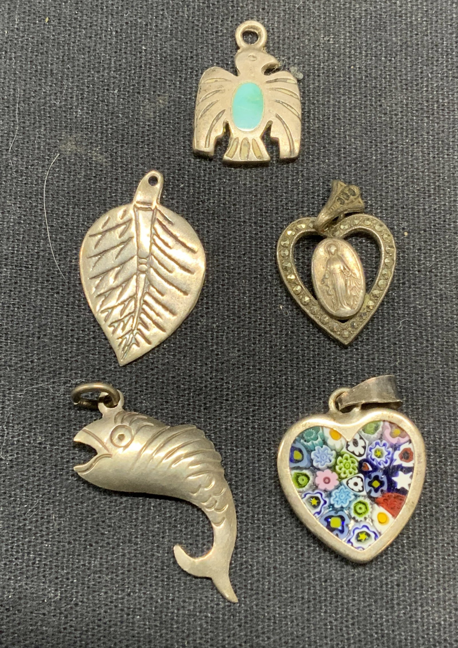 Lot 5 Vintage Sterling Silver Pendants: Lot of 5 vintage sterling silver pendants. 1 piece unmarked, tests for sterling using PuriTEST kit. Art glass heart pendant, virgin of Guadalupe marcasite pendant, fish pendant, leaf pendant, and bird
