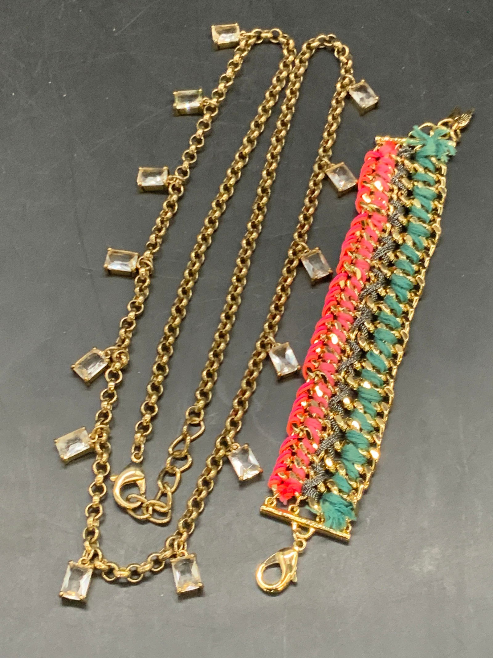2 Gold Tn Metal Crystal Necklace & Woven Bracelet: A gold tone metal chain link necklace featuring square form faceted crystals and a gold tone metal bracelet featuring woven multicolored fabric. Both pieces possess lobster claw clasp closures. Bracel