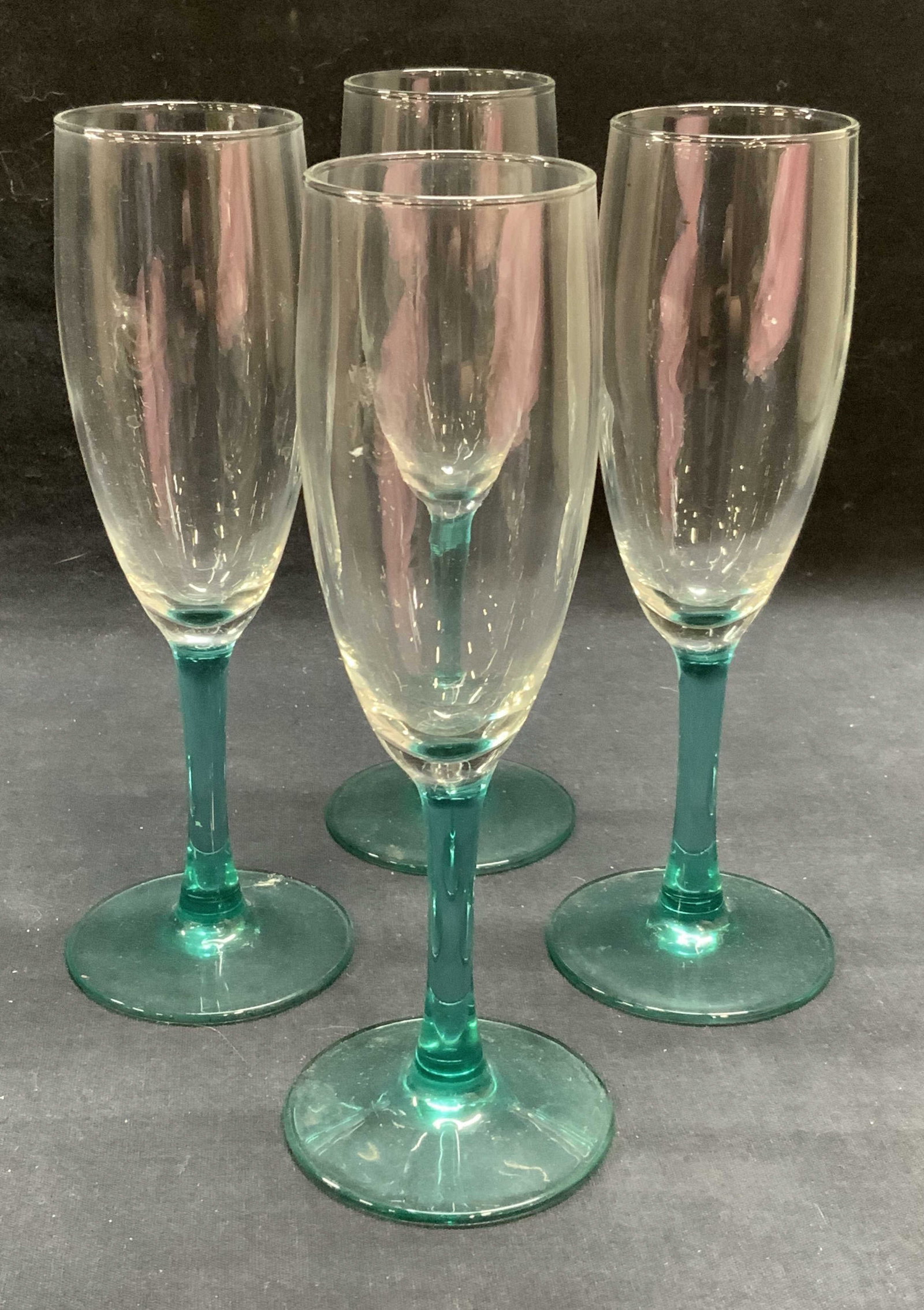 Set 4 Teal Blue Stem Wine Glasses: Set of 4 clear to teal blue wine glasses. Narrow stem with base and narrow body glasses. Measures approx. 2.75 x 7.75 inches each. Some surface wear to all pieces consistent with exposure. Wine glasse