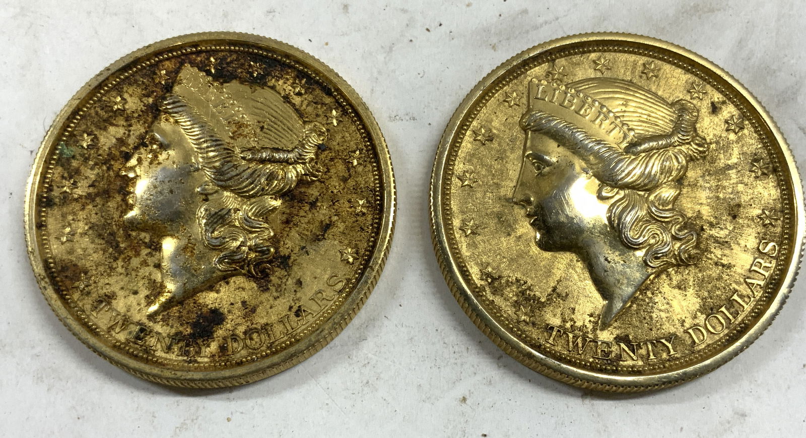 Lot 2 Gilt Metal Coin Coasters: Lot includes 2 coasters. Each have gold toned gilt finishes. Each are circular shaped with coin form. Each measures approximately 3.75 inches diameter. Coasters, coin coasters, gilt metal coasters, gi