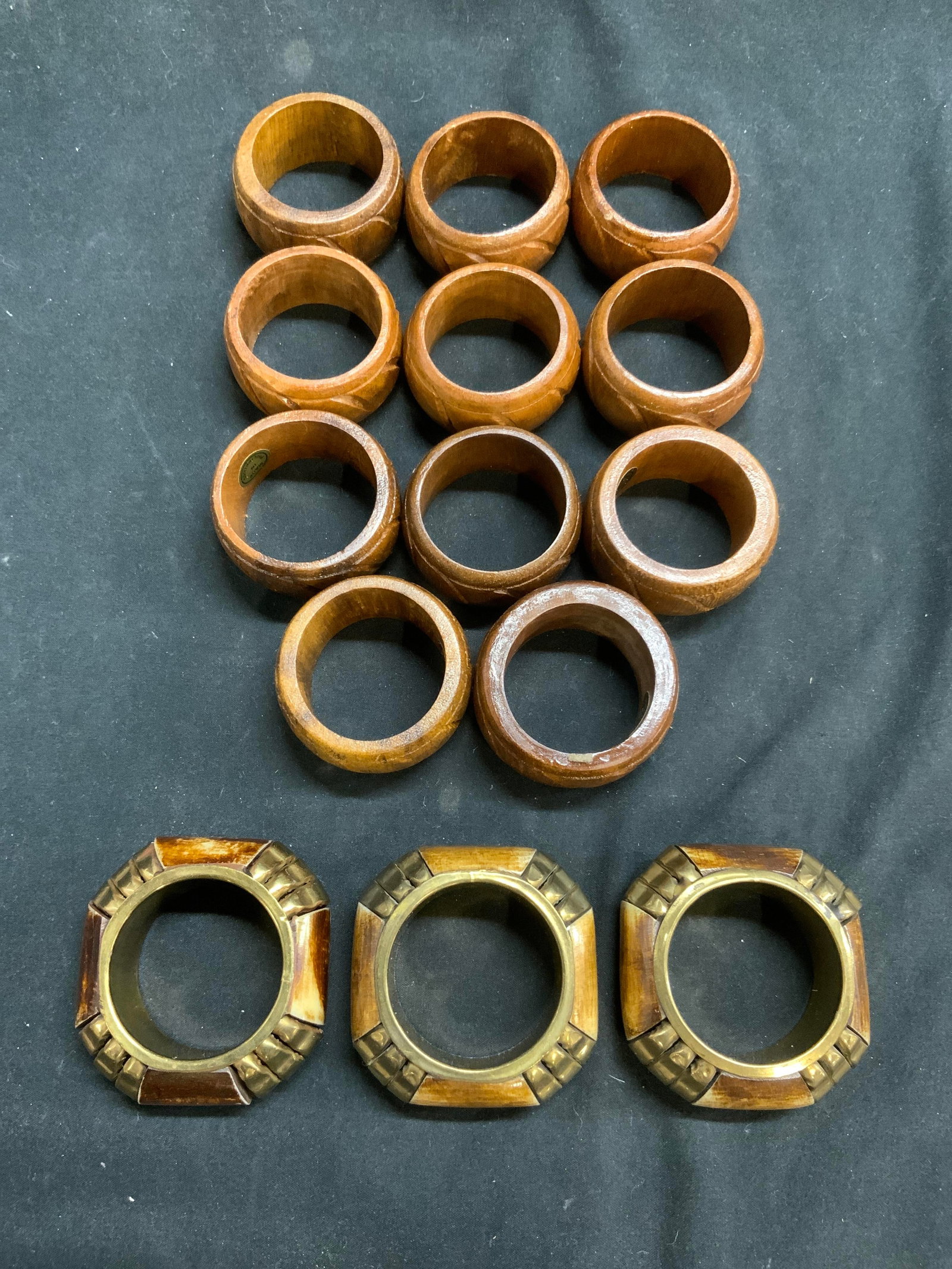 Lot 14 Wood Bone & Gilt Metal Napkin Rings: Lot includes 14 napkin rings. 3 bone and gilt metal, 11 wooden. Wooden napkin rings have carved relief detail. Bone and gilt metal napkin rings. Measure approximately 2.25 inches wide & deep. Napkin r