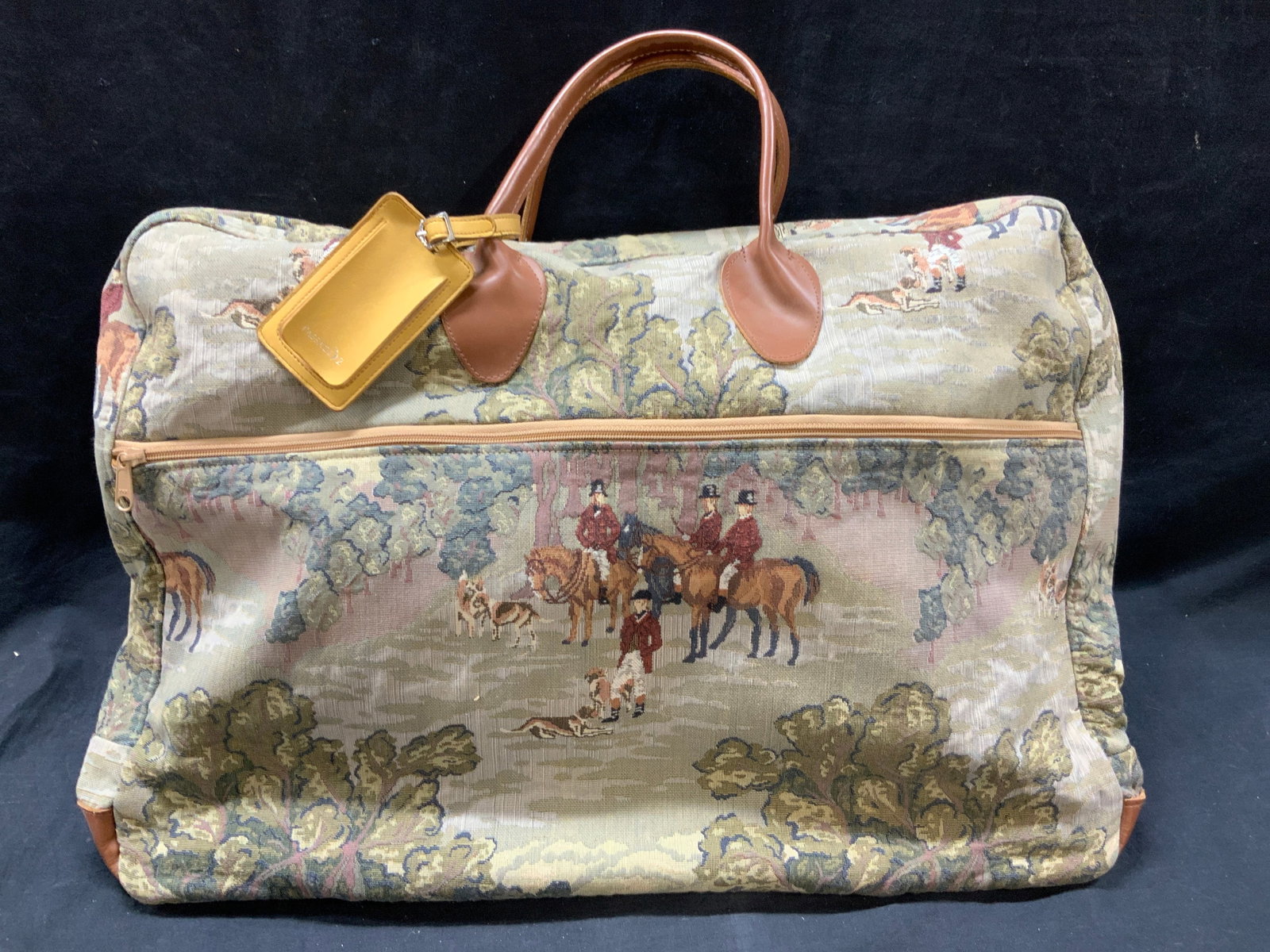 Coarc Bags Needlepoint Style Travel Bag: Marked on tag Coarc Bags. Exterior has English style embroidery of a an English scene of hunters of their houses in the wilderness. Complete with leather top handles and exterior and interior pockets.