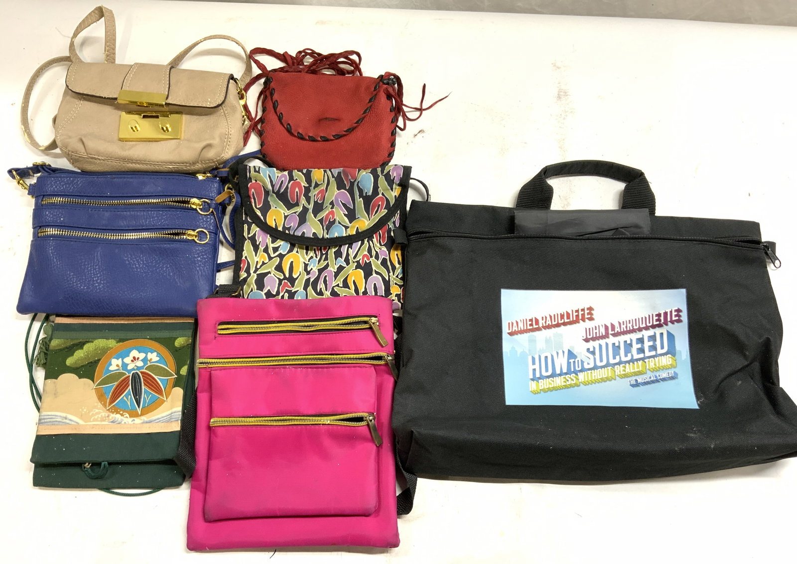 Lot 7 Clutches, Purses, Handbags: Lot includes 1 beige leather handbag with gold toned clasp & 2 pockets, 1 blue leather handbag with 5 pockets, 1 multi toned nylon floral detailed handbag with flap & snap button clasp, 1 pink toned n