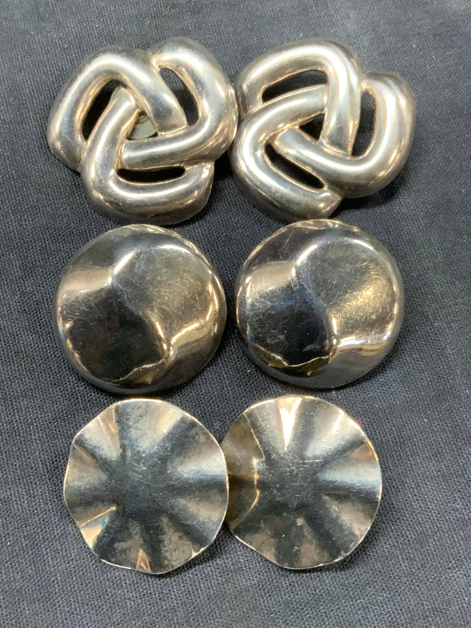 Lot 3 Pr Sterling Silver Stud Earrings, Mexico: Lot of 3 pairs of Stud backed earrings 2 pairs marked sterling and Mexico on backsides. Approx 1.5 and 1.25 inches wide, one in an infinite knot design, the other a swirled button earring, and 1 pair