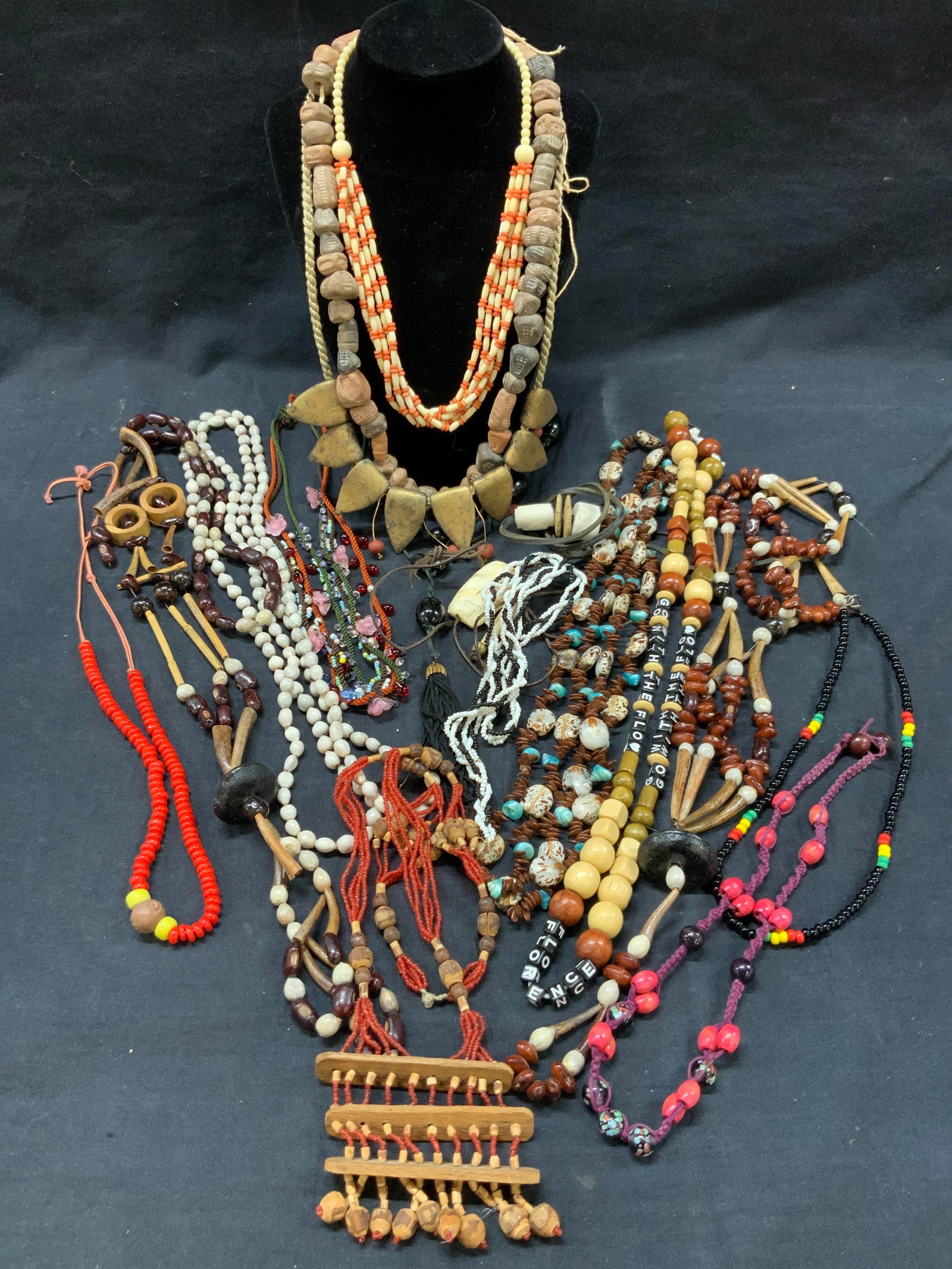 Lot 20+ Crafted Wood & Shell Beaded Necklaces: Lot of approx 21 necklaces made of wooden beads, shells, ceramic beading and glass seed beads. Necklaces range from 8 inches long to 25 inches long. Highlights being. 1 necklace made of ceramic crafte
