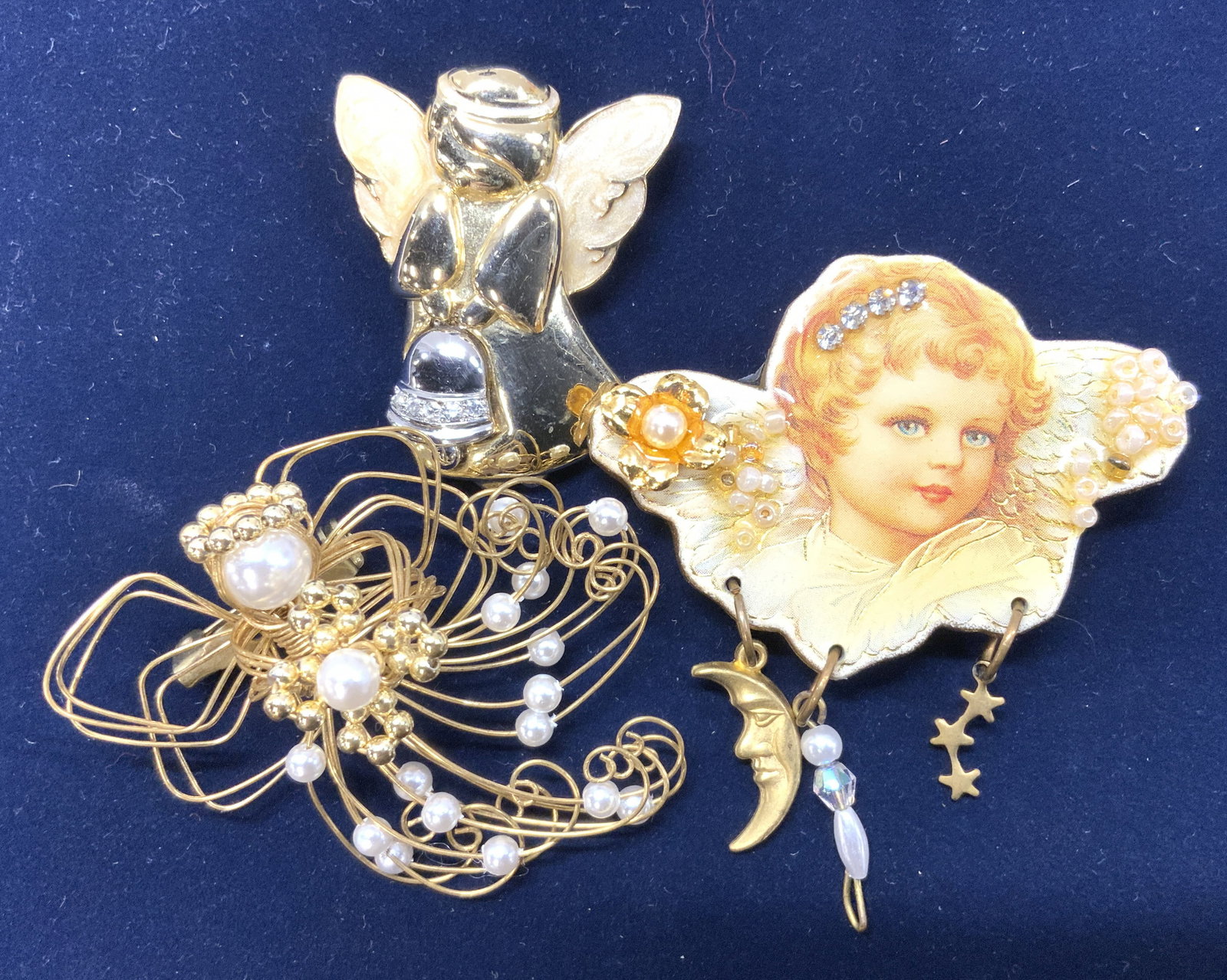 3 Gold Tone Angel Brooches, Creations by Frances: Lot of 3 angel brooches. Hand crafted gold tone wrapped wire with faux pearls , 2 x 2 in. Another is gold tone with enamel wings holding a bell, measures 1.5 x 1.5 in. Hand made brooch with label on b