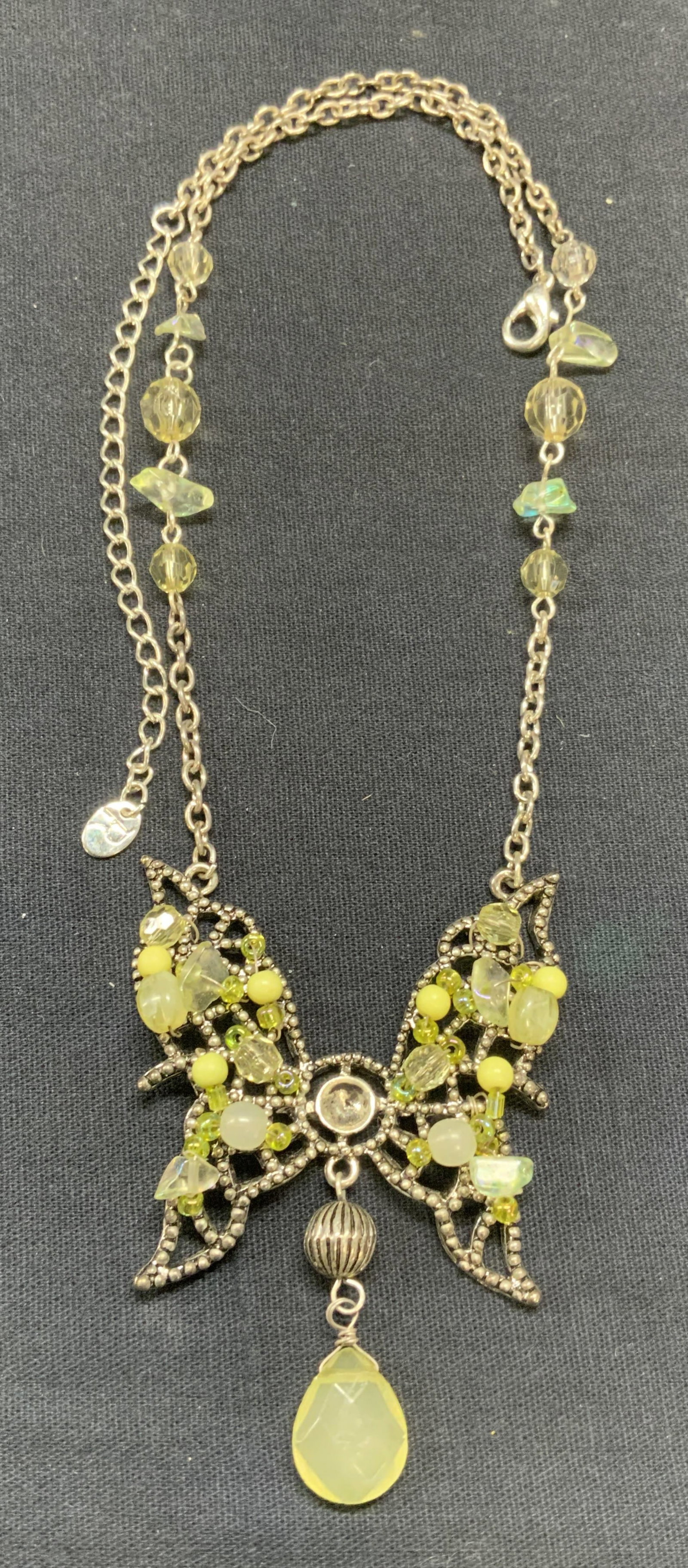 Signed Green Crystal Butterfly Pendant Necklace: Signed R silver tone necklace with green crystal decorated butterfly pendant. Signed on hang tag. Drop length approx. 8 inches. Some scratching observed, 1 crystal needs replacement. Estate jewelry, c