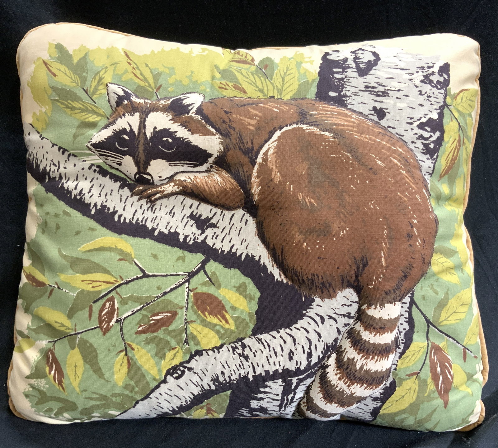 Welted Pillow W Beveled Raccoon: Pillow has depiction of raccoon climbing a tree. Raccoon derailed area is beveled. Piece has welted edges. Pillow appears to be cotton. Pillow measures approximately 15 inches wide 12 inches tall 4.5 