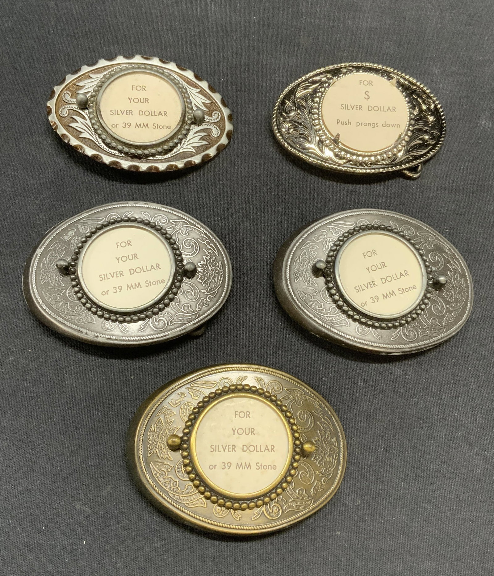 Lot 5 Silver & Gold Tone Belt Buckles: Lot of 5 silver and gold tone embossed scroll belt buckles. Each has window for displaying silver dollar, 39 mm stone, or other accessory. Larger belt buckles measure approx. 3.5 x 2.5 inches. All pie